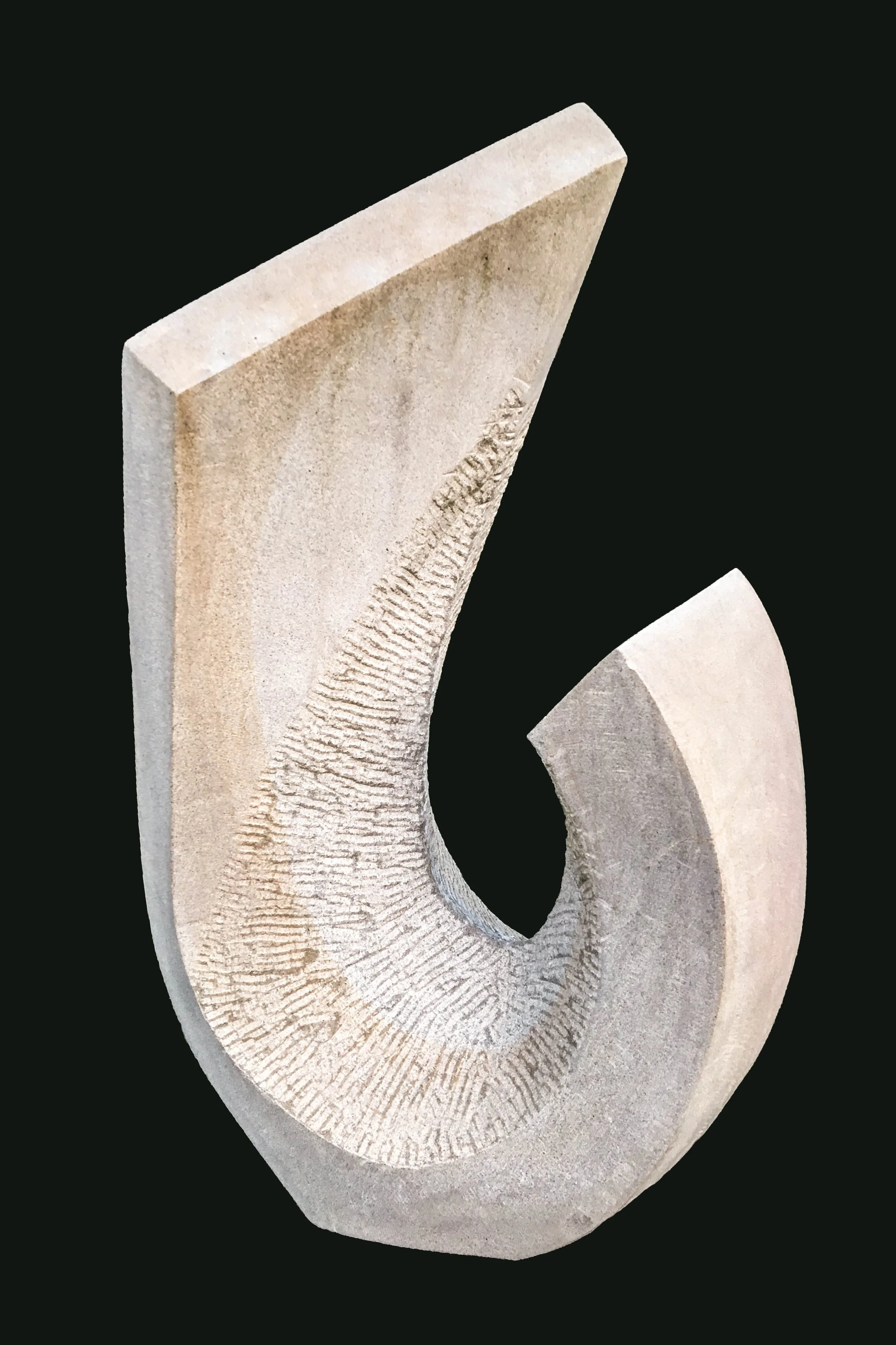 A sculptural art piece shaped like a stylized number six, made of light-colored stone with textured and smooth surfaces, set against a black background.