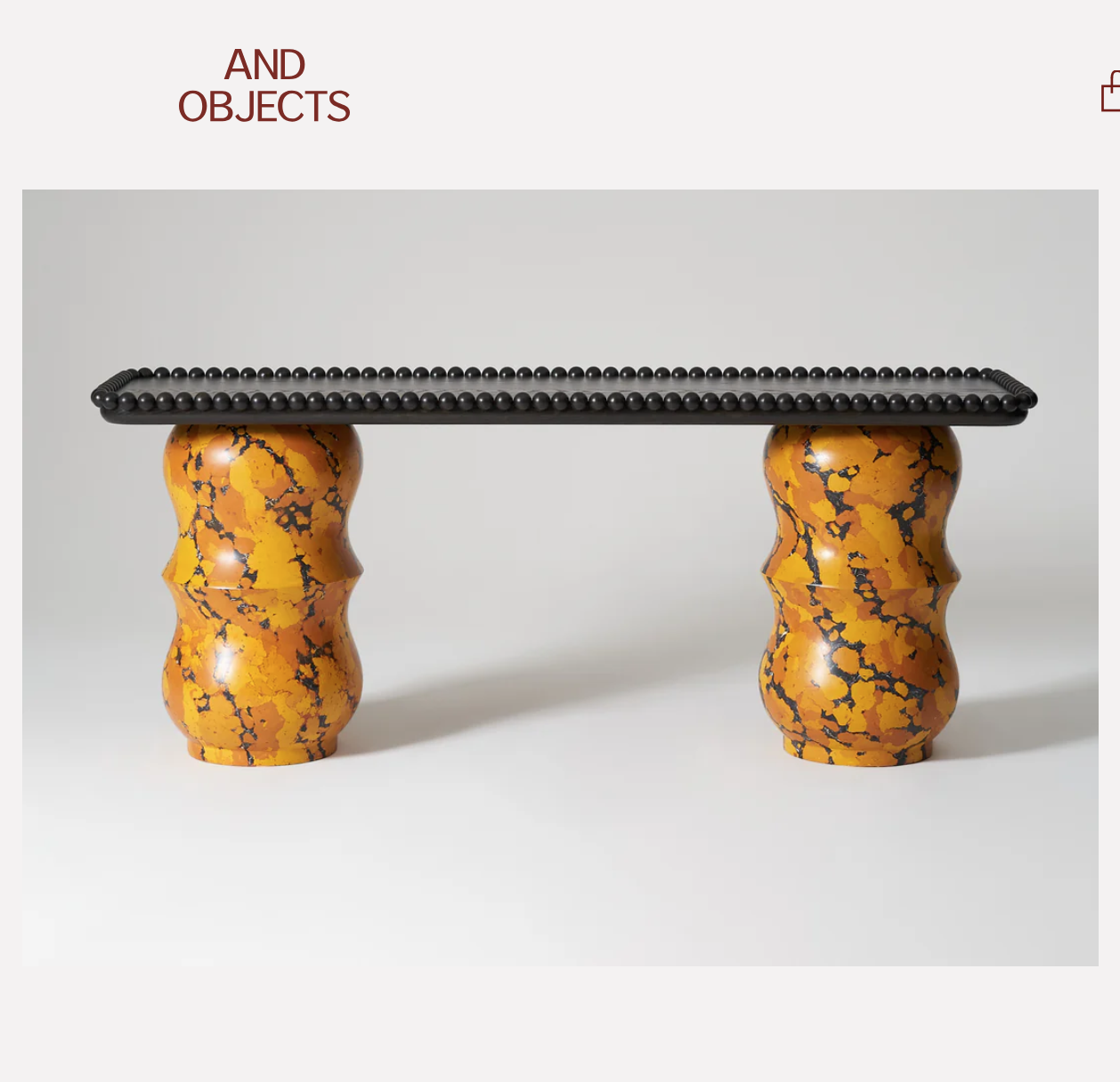 A rectangular table with a black beaded top and orange and black marbled turned bases.