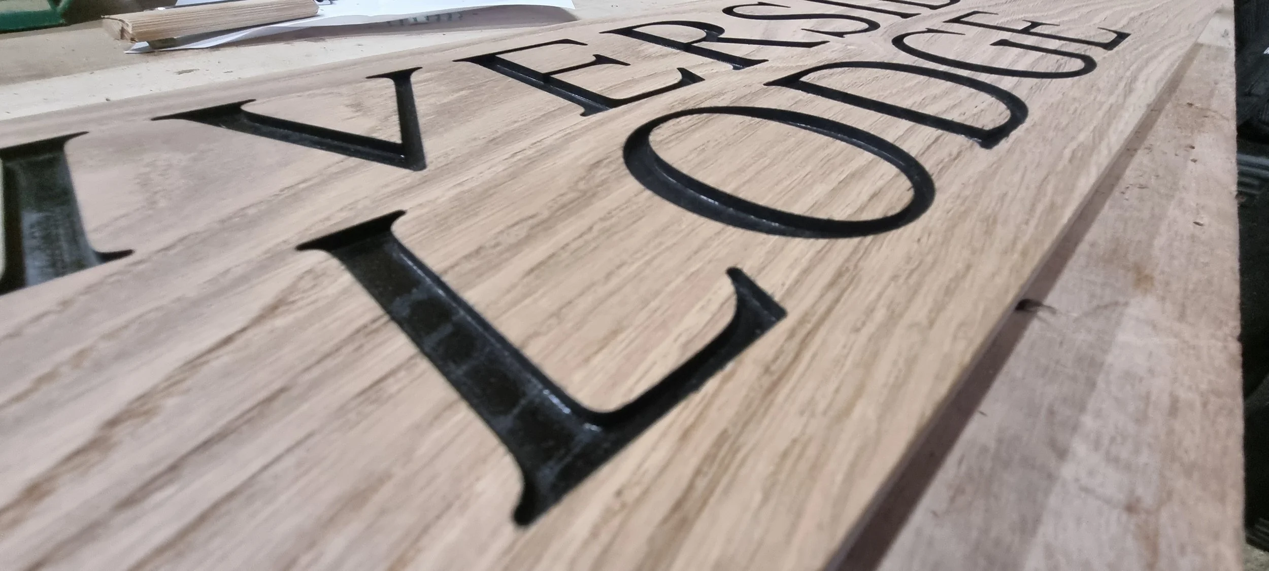 Close-up of a wooden sign with cut-out black letters spelling "VET RAP" on a worktable in a workshop.