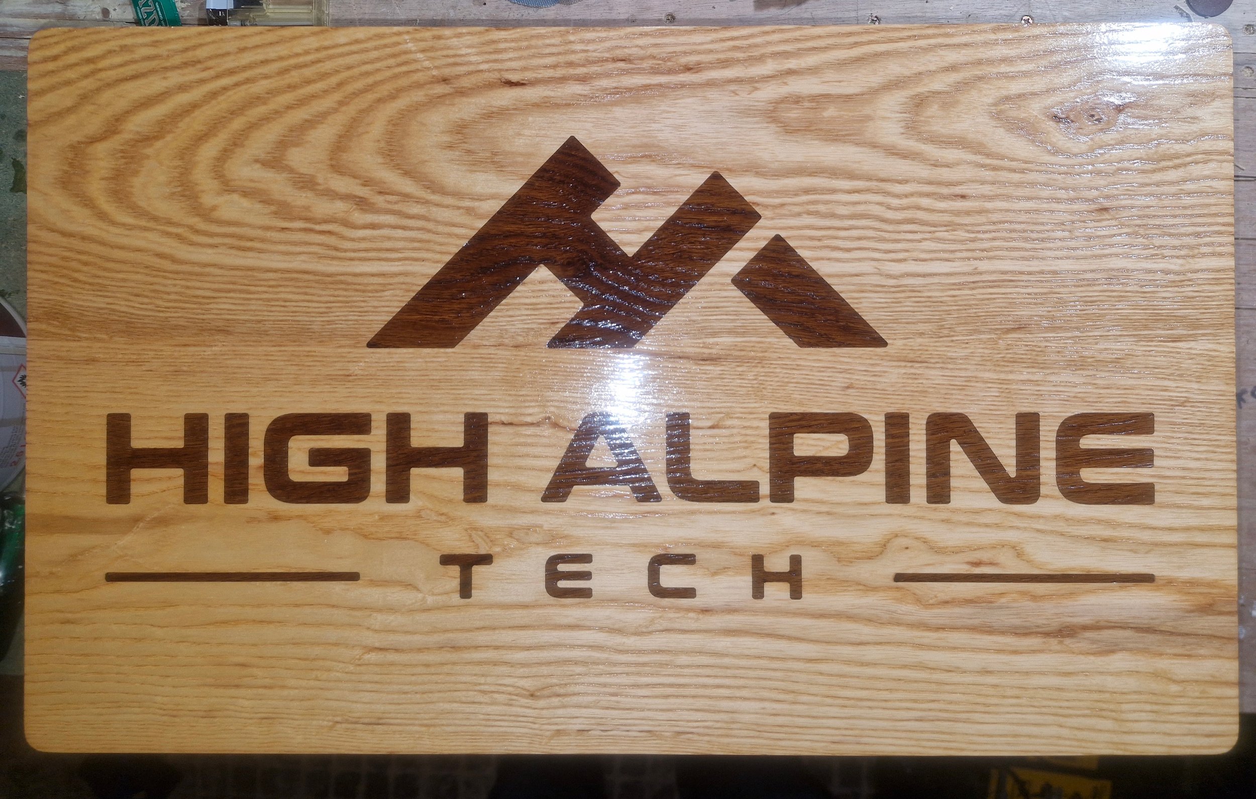 Wooden sign with a mountain logo and the text "High Alpine Tech" engraved.