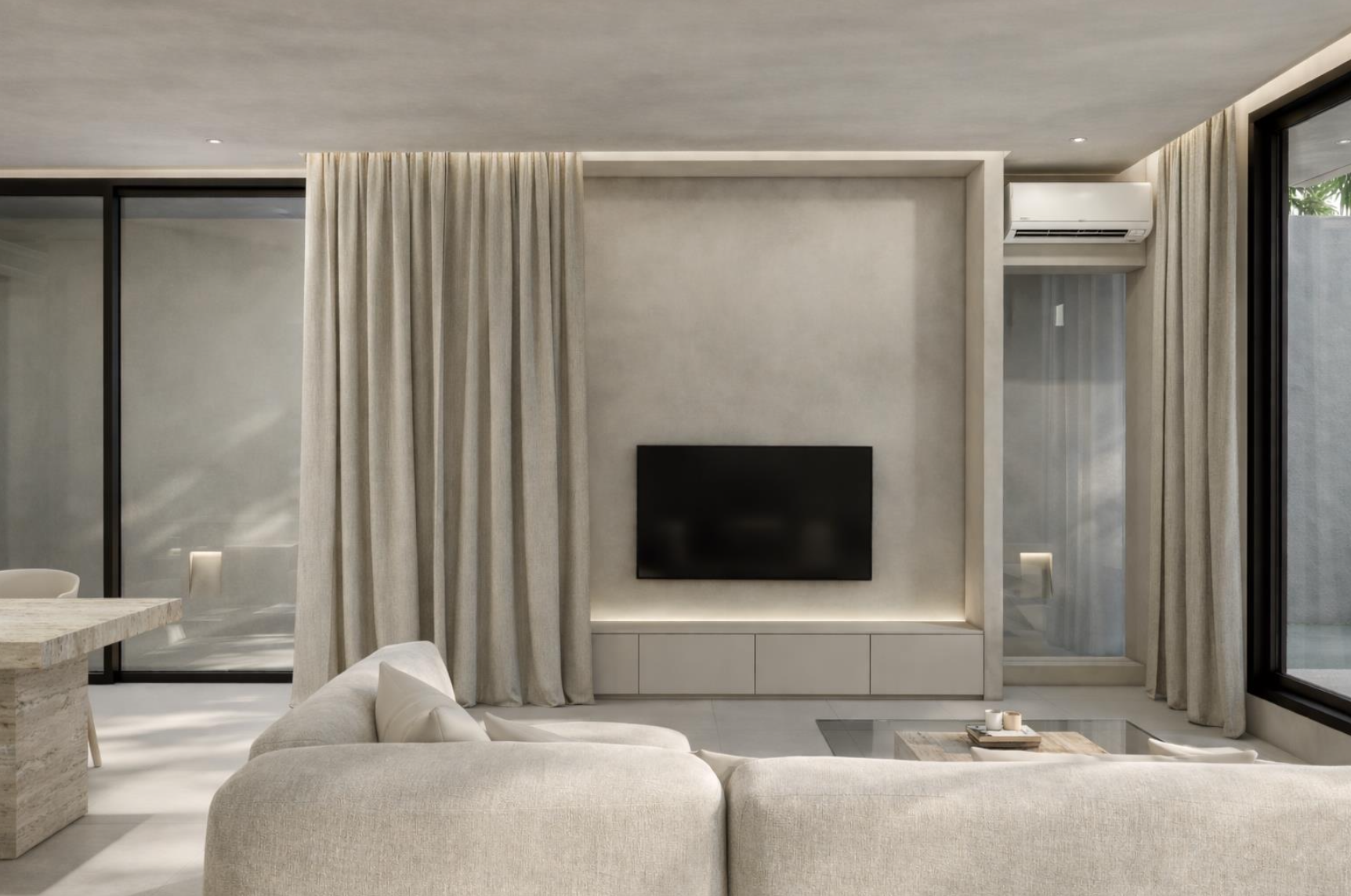 Modern living room with a beige sectional sofa, a flat-screen TV on the wall, floor-to-ceiling curtains, large windows, and minimal decor.