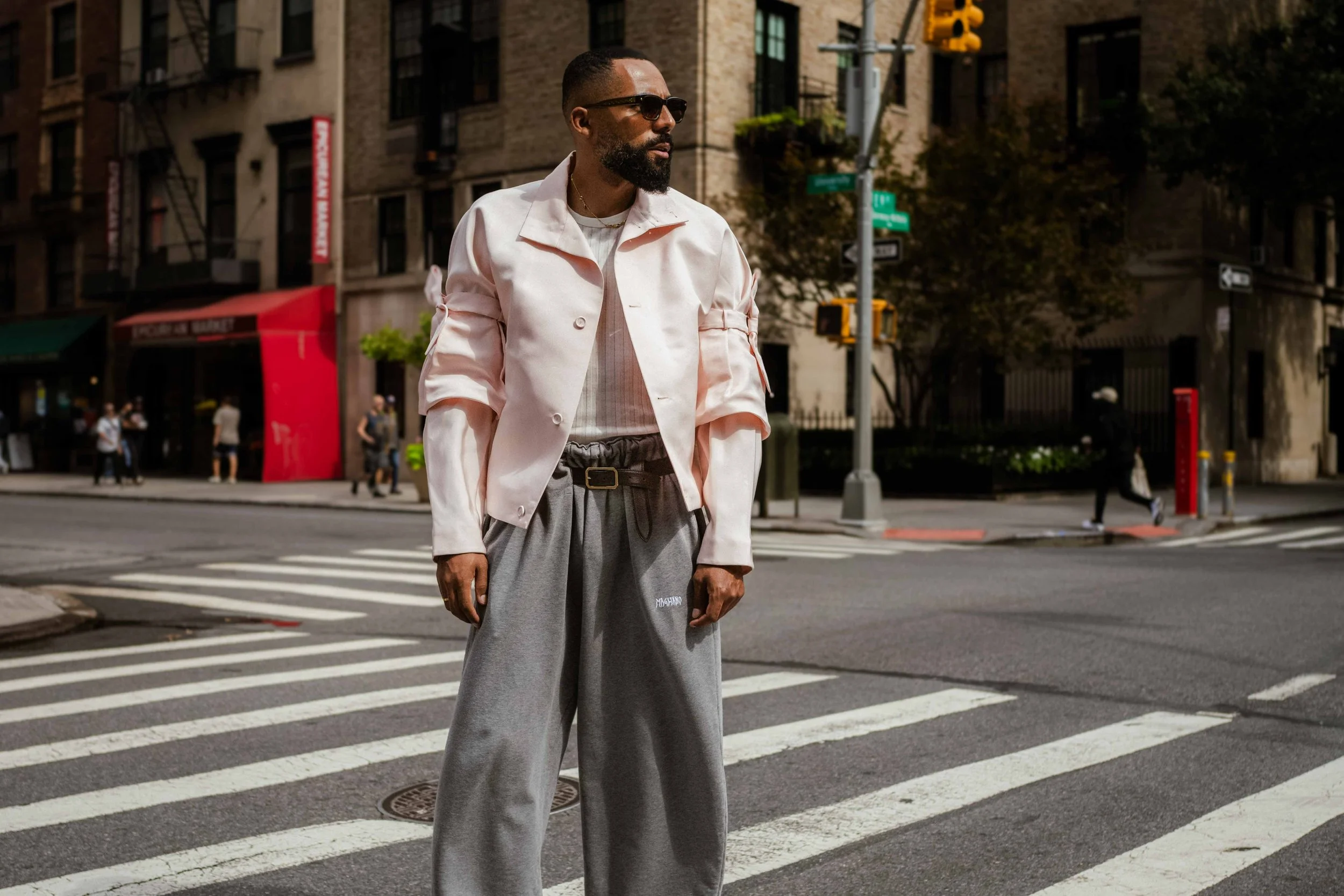Street style photo of Jean-Claude Mpassy during New York Fashion Week. He is wearing a pink Dior jacket and some grey sweatpants from Magliano.