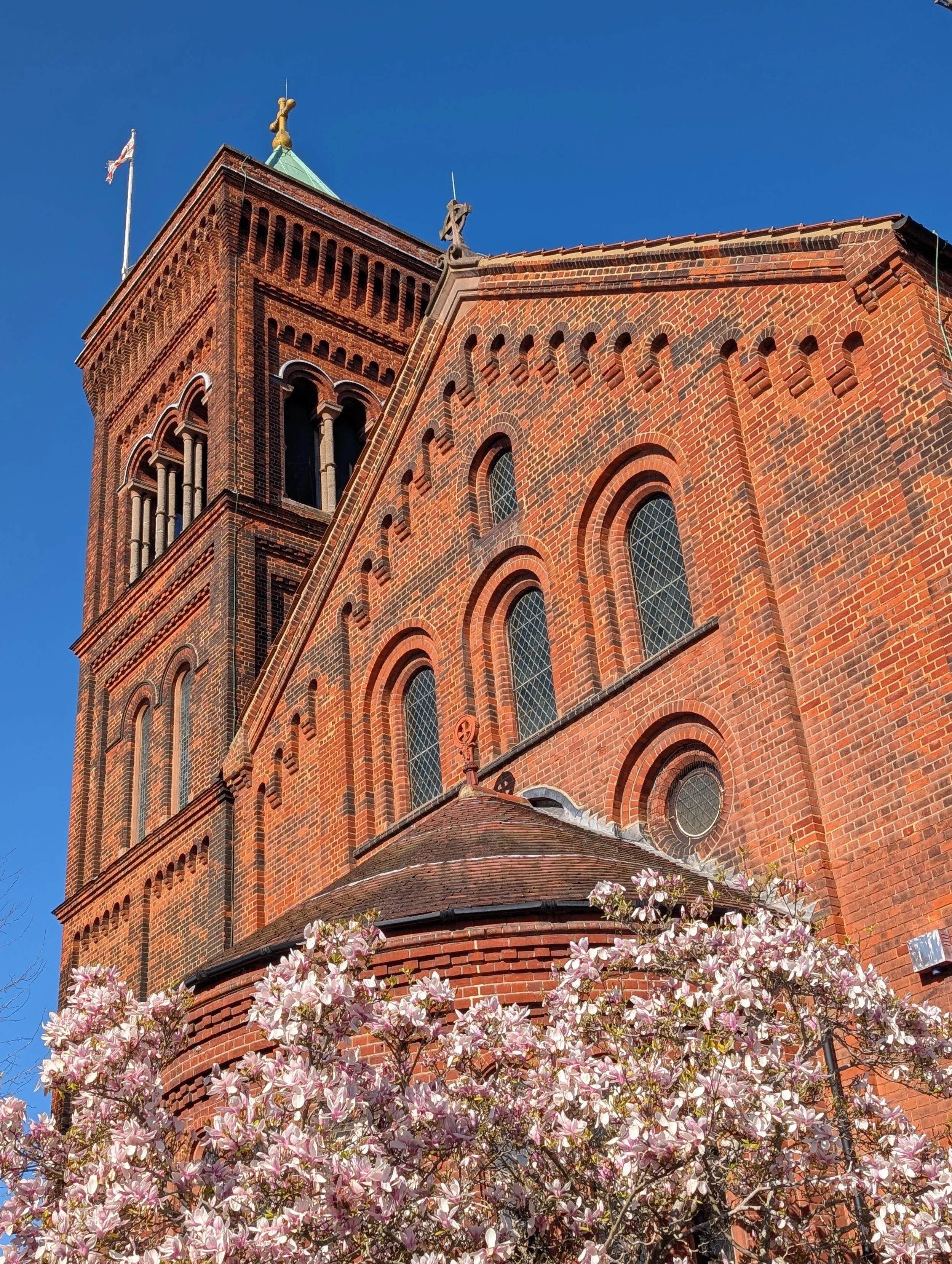 Red brick church tower in the sun against clear blue sky