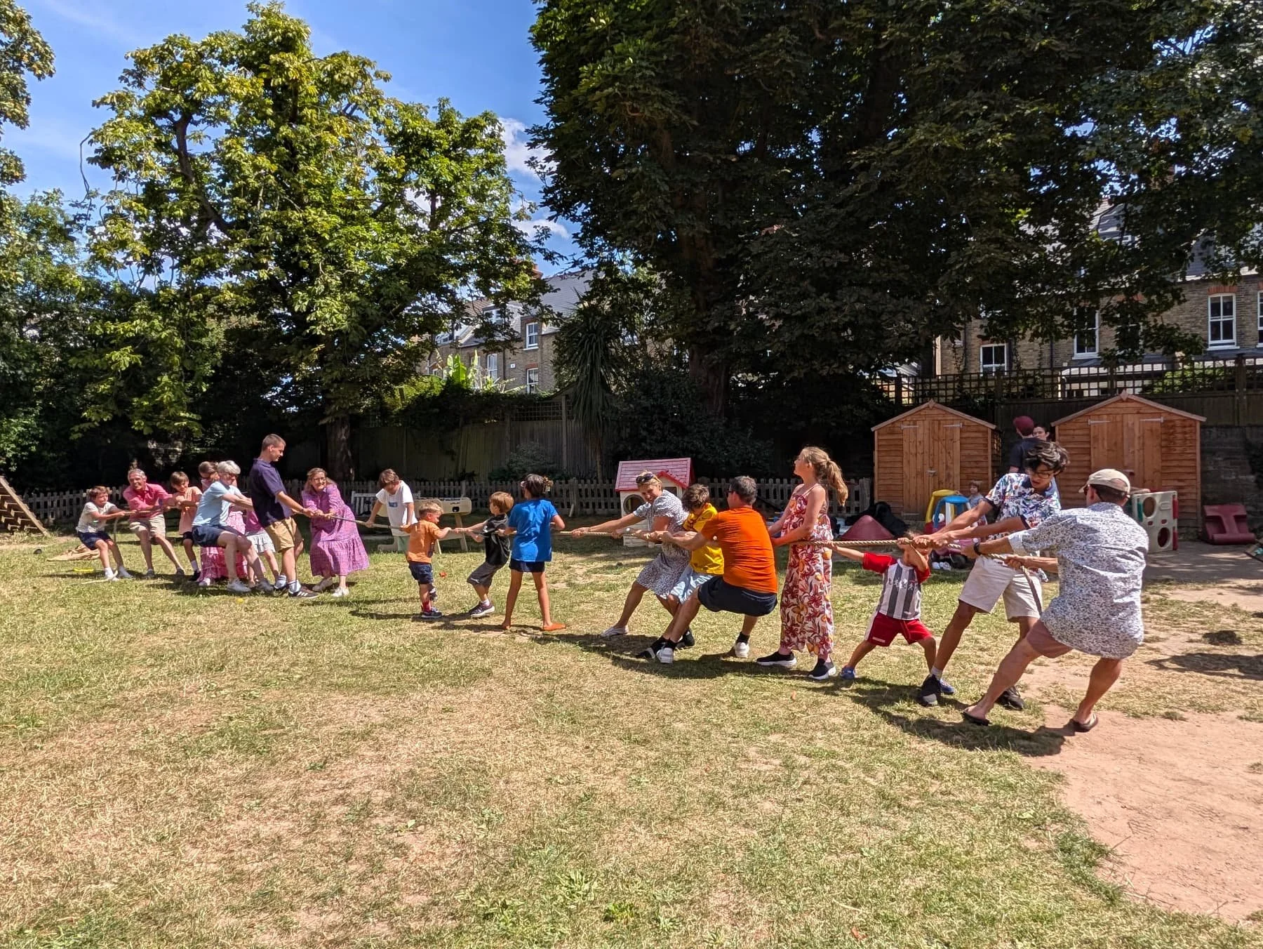 Children and Adults playing Tug-of-War in a garden