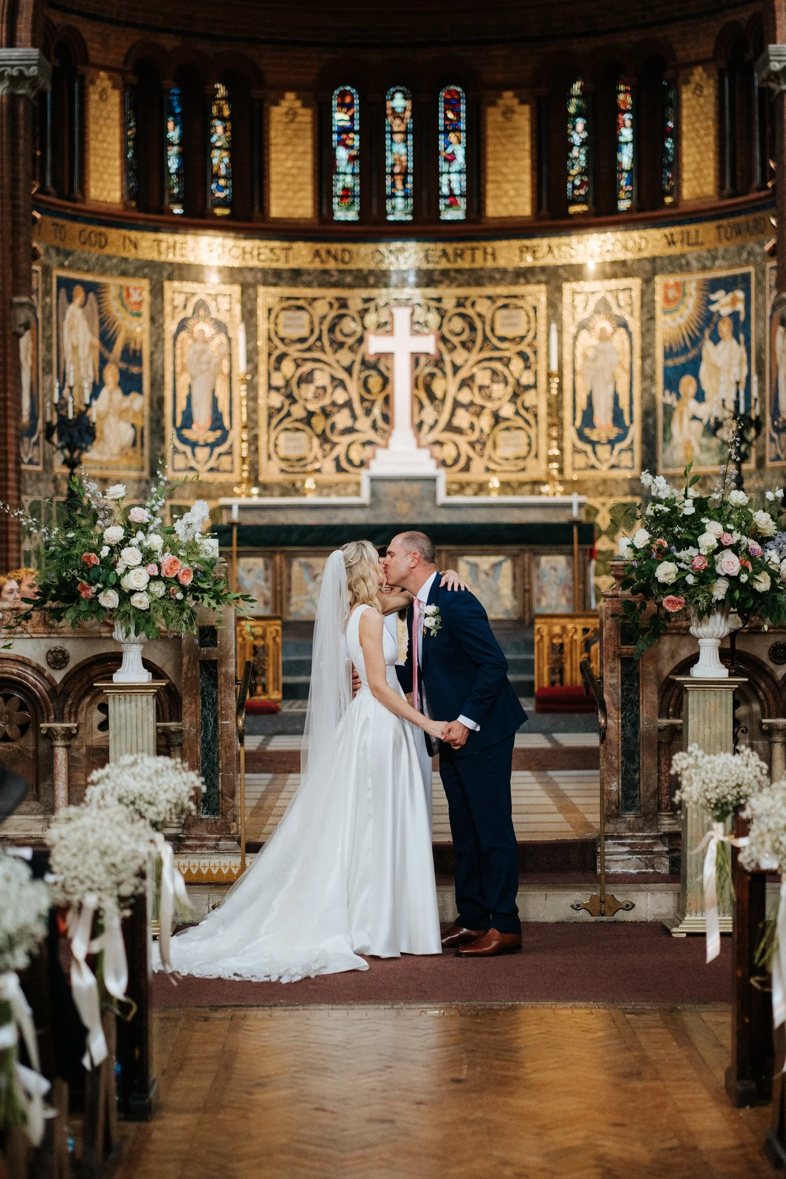 A newly wed couple kiss at the altar