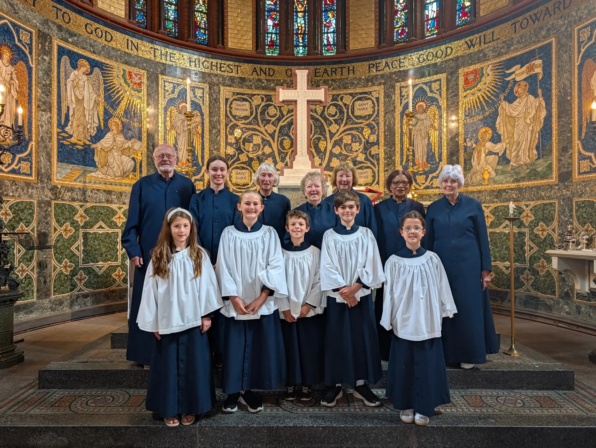 Full choir stand together for a group photo in front of the altar