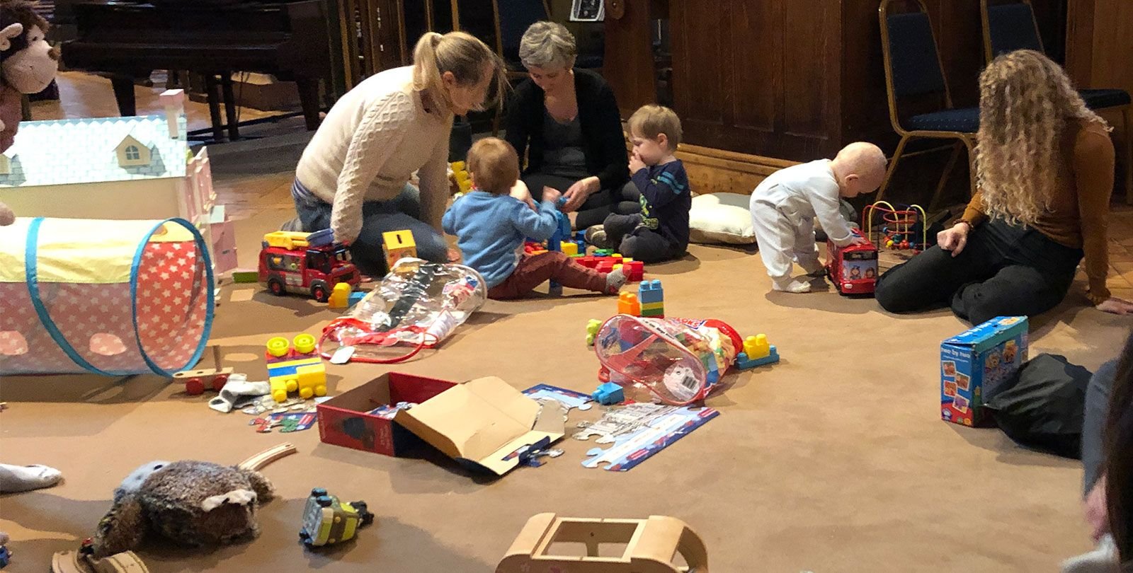 toddlers and their carers play on the floor with toys