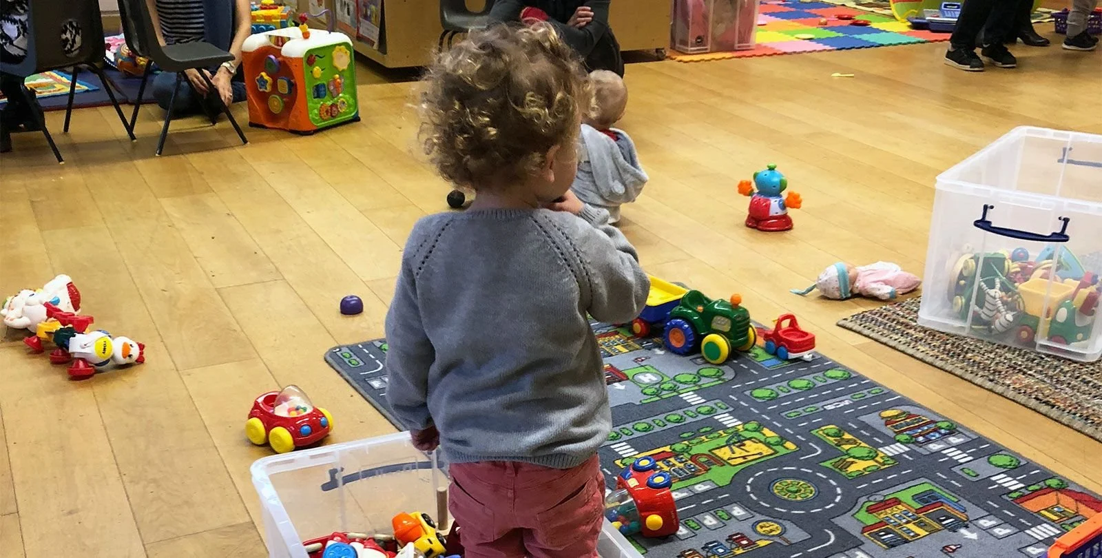 a toddler and a baby play in a room filled with toys
