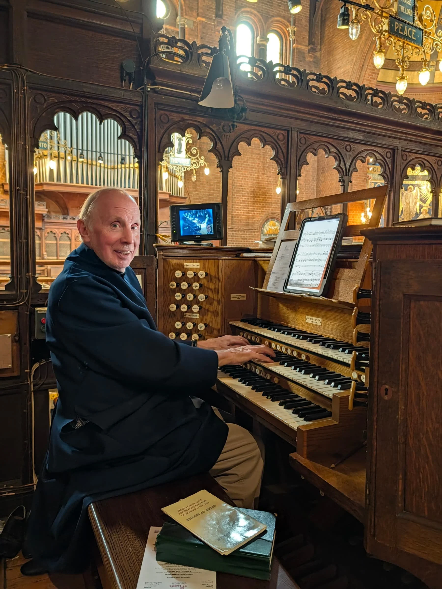 The musical director sits smiling and playing the church organ
