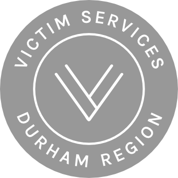 Gray circular logo with white text reading 'Victim Services Durham Region' surrounding a central stylized check mark or tick in the middle.