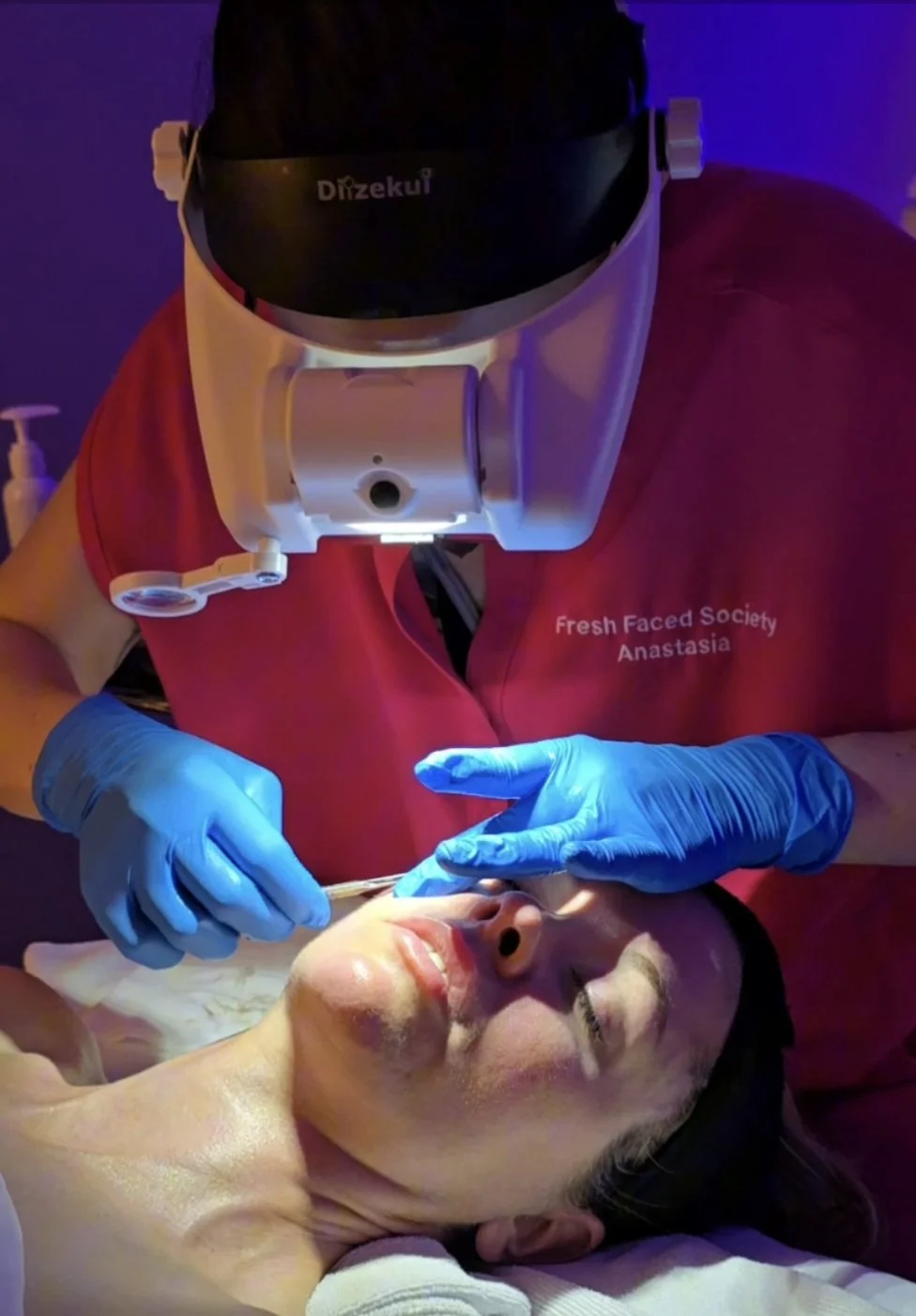 Woman dermaplaning another woman's face.