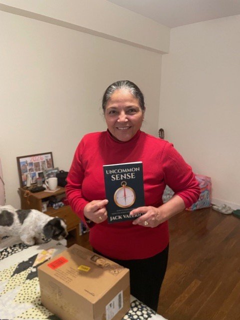 Carmen, a former student of Jack Valerio, holding a copy of Uncommon Sense by Jack Valerio.