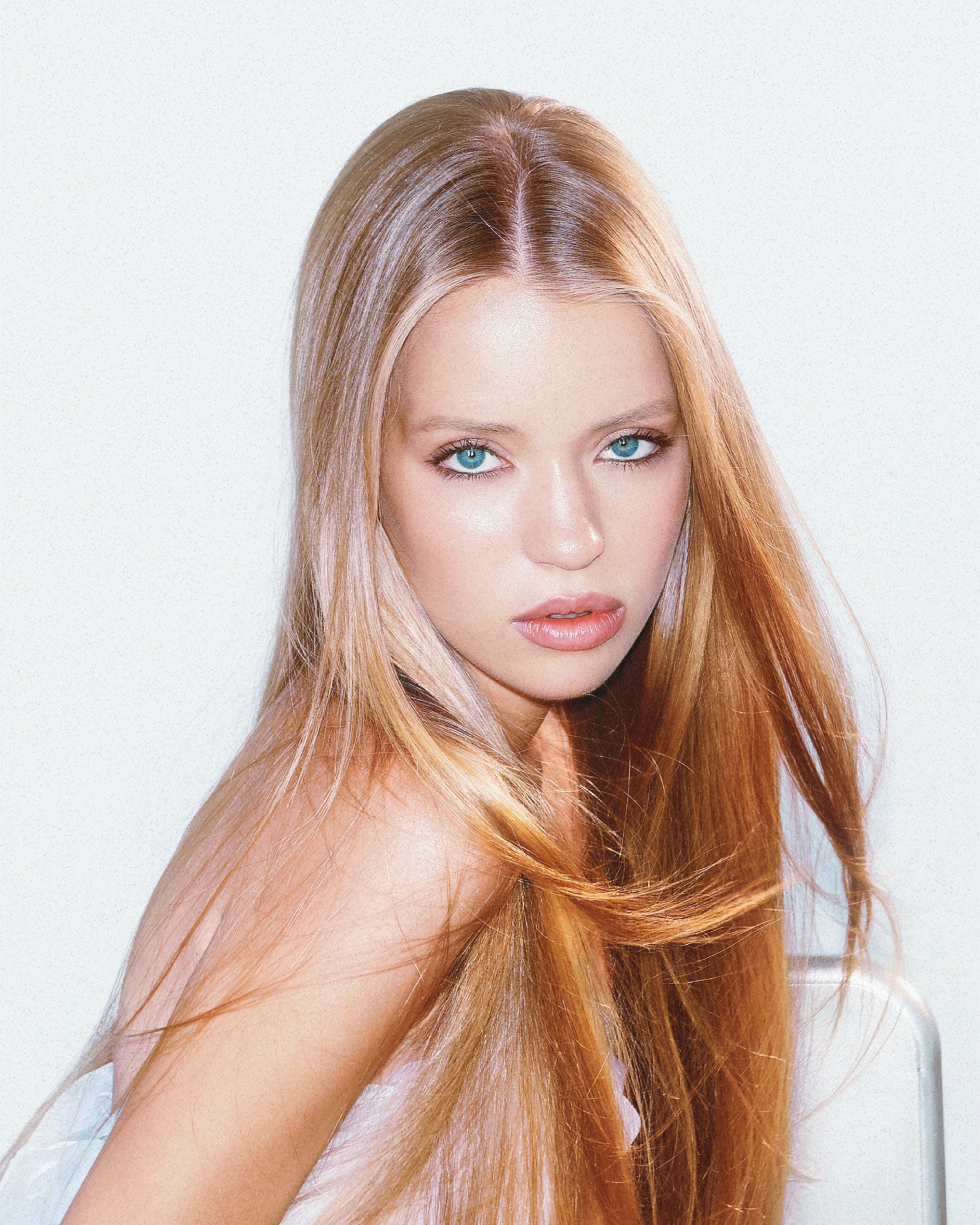 A young woman with long red hair and blue eyes looking at the camera against a plain white background.