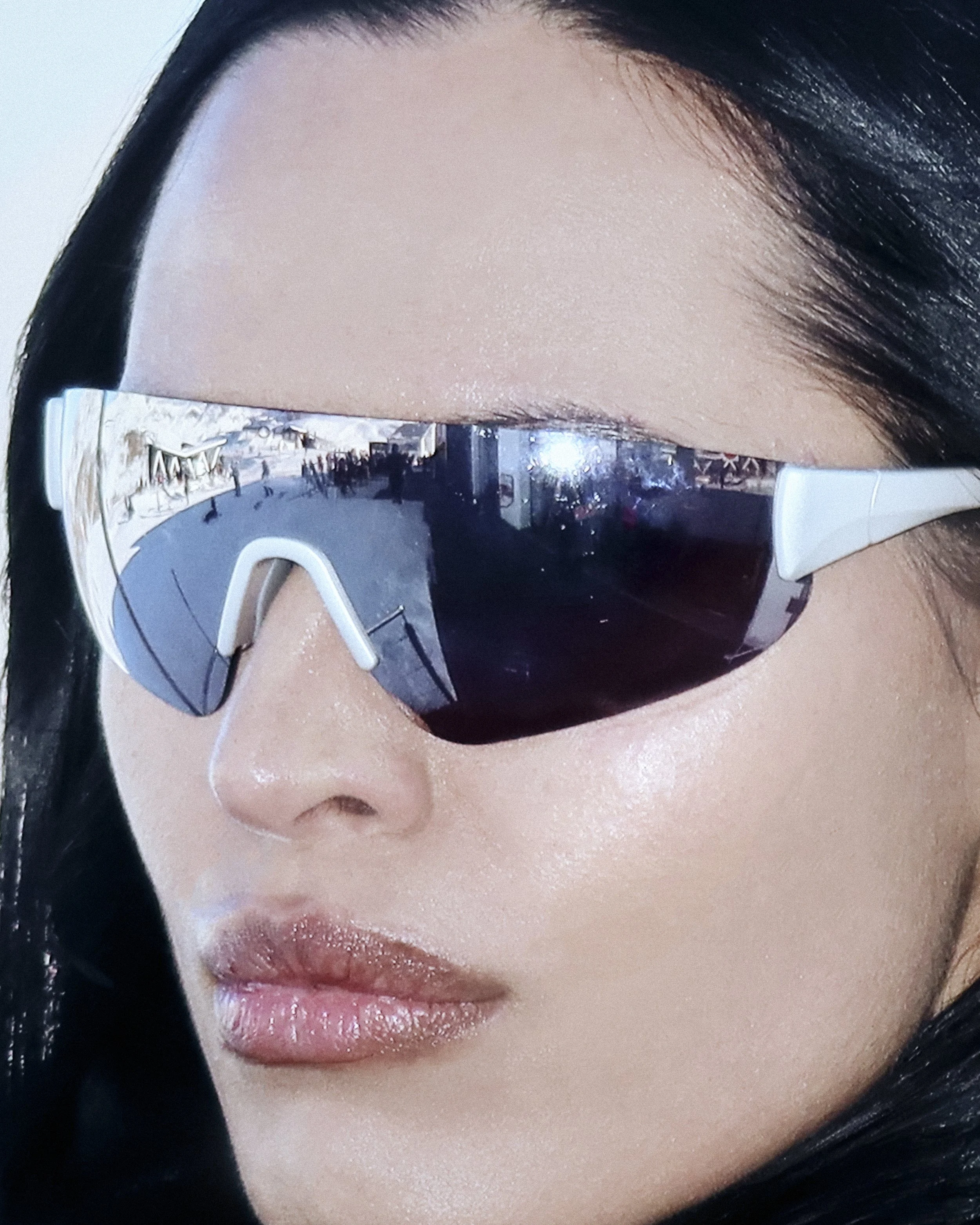Close-up of a woman's face wearing stylish sunglasses with reflective lenses.