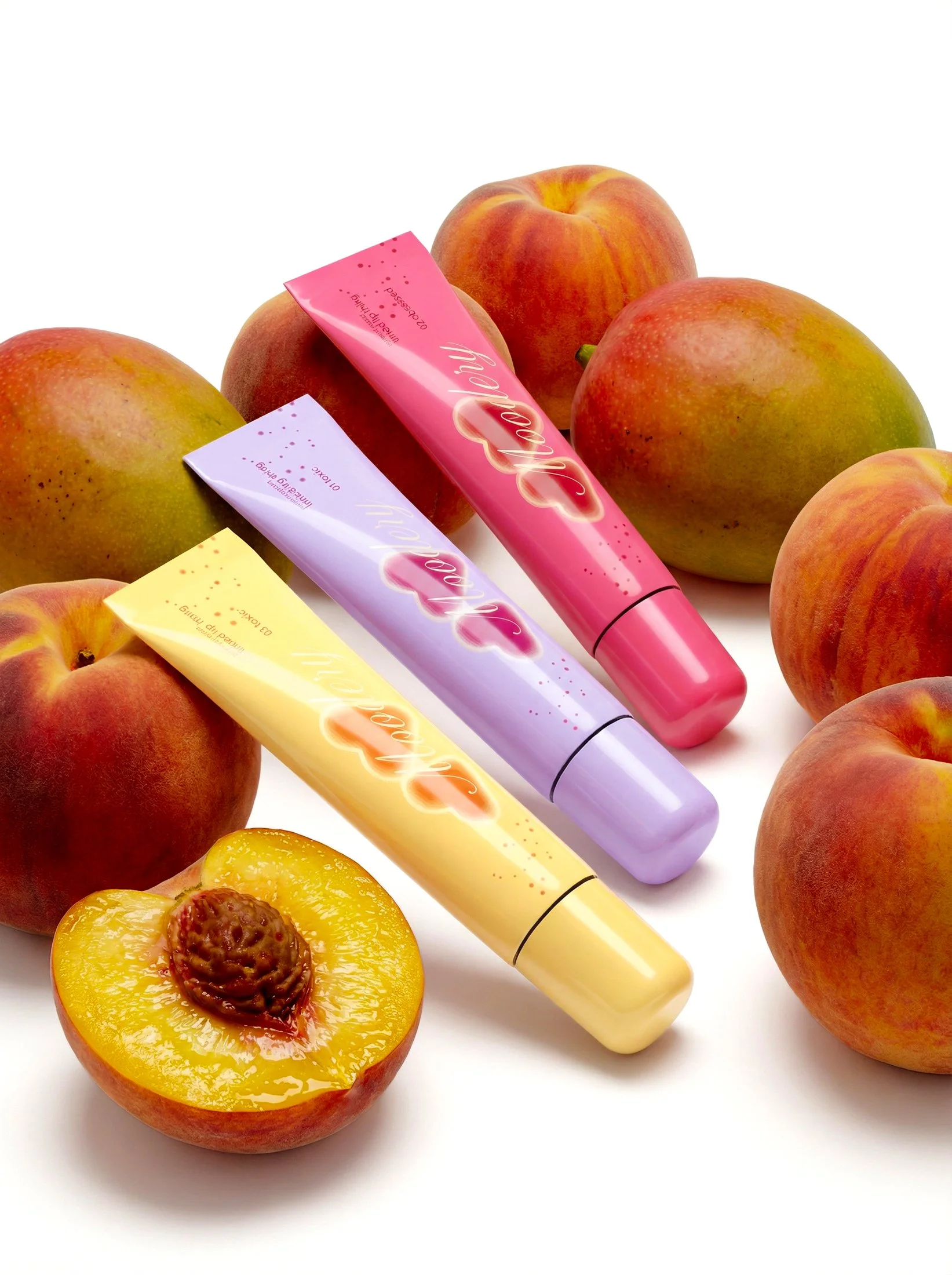 Peach-flavored lip gloss tubes in pink, purple, and yellow, surrounded by fresh peaches, one cut in half showing the pit.