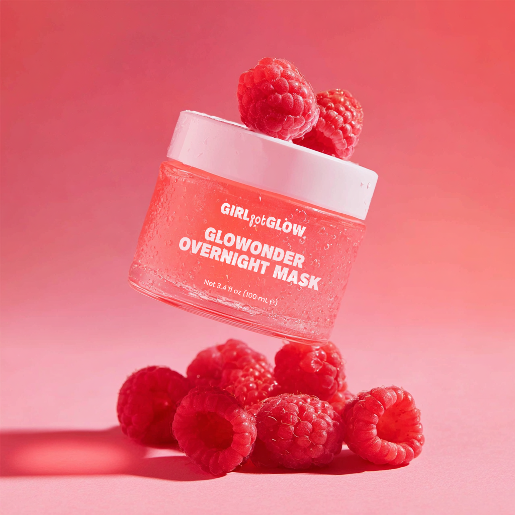 A jar of Girl Got Glow Glowonder Overnight Mask with raspberries around and on top of the jar, set against a pink background.