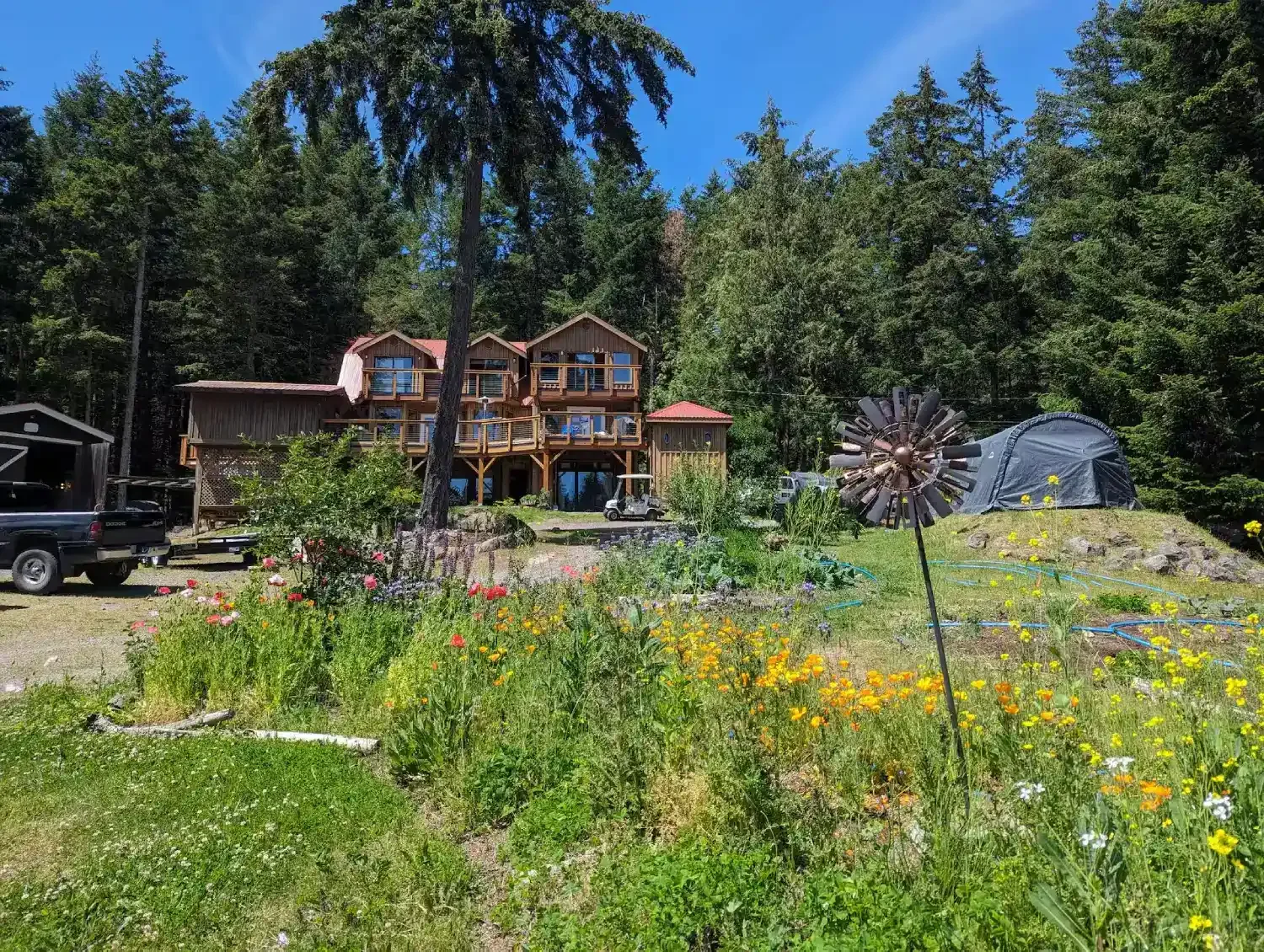 Galiano cabin with red roof framed by forest and colourful flowers