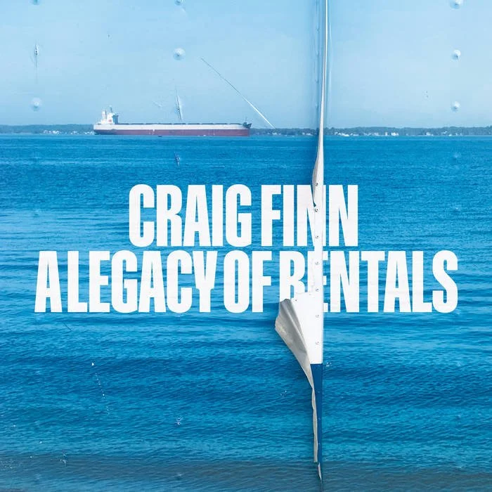 A book cover titled 'Craig Finn: A Legacy of Rentals' features a scene with a large cargo ship in the water. The background shows a distant shoreline with buildings under a cloudy sky.