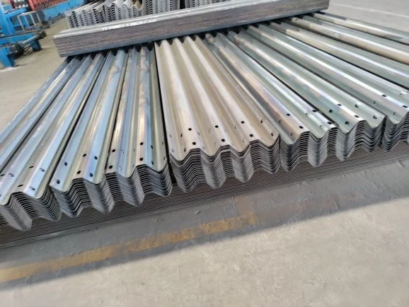 Stacks of wavy metal roofing sheets with metal bars on top in a warehouse or factory setting.