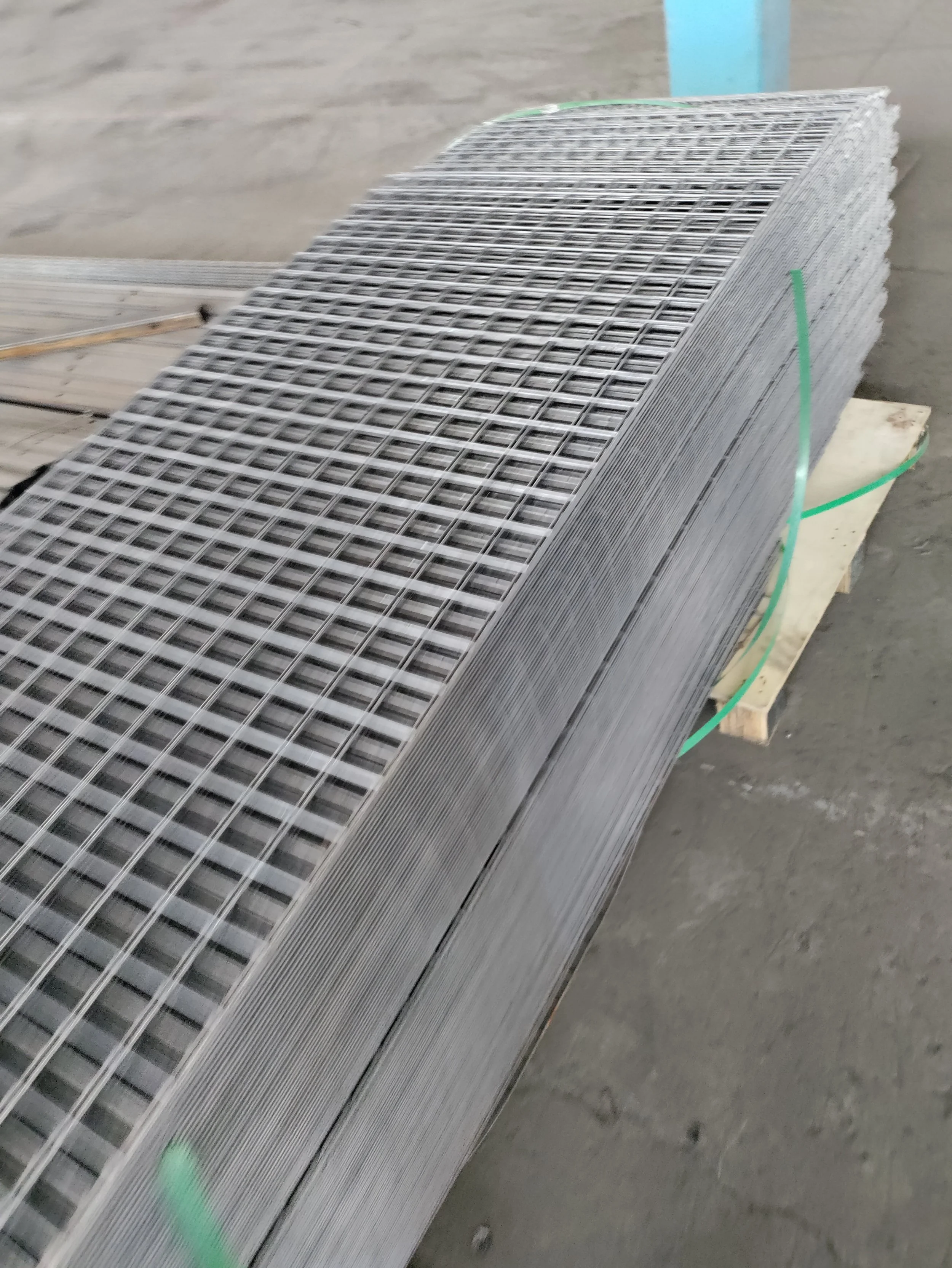 Stack of metal wire mesh sheets on a wooden platform.
