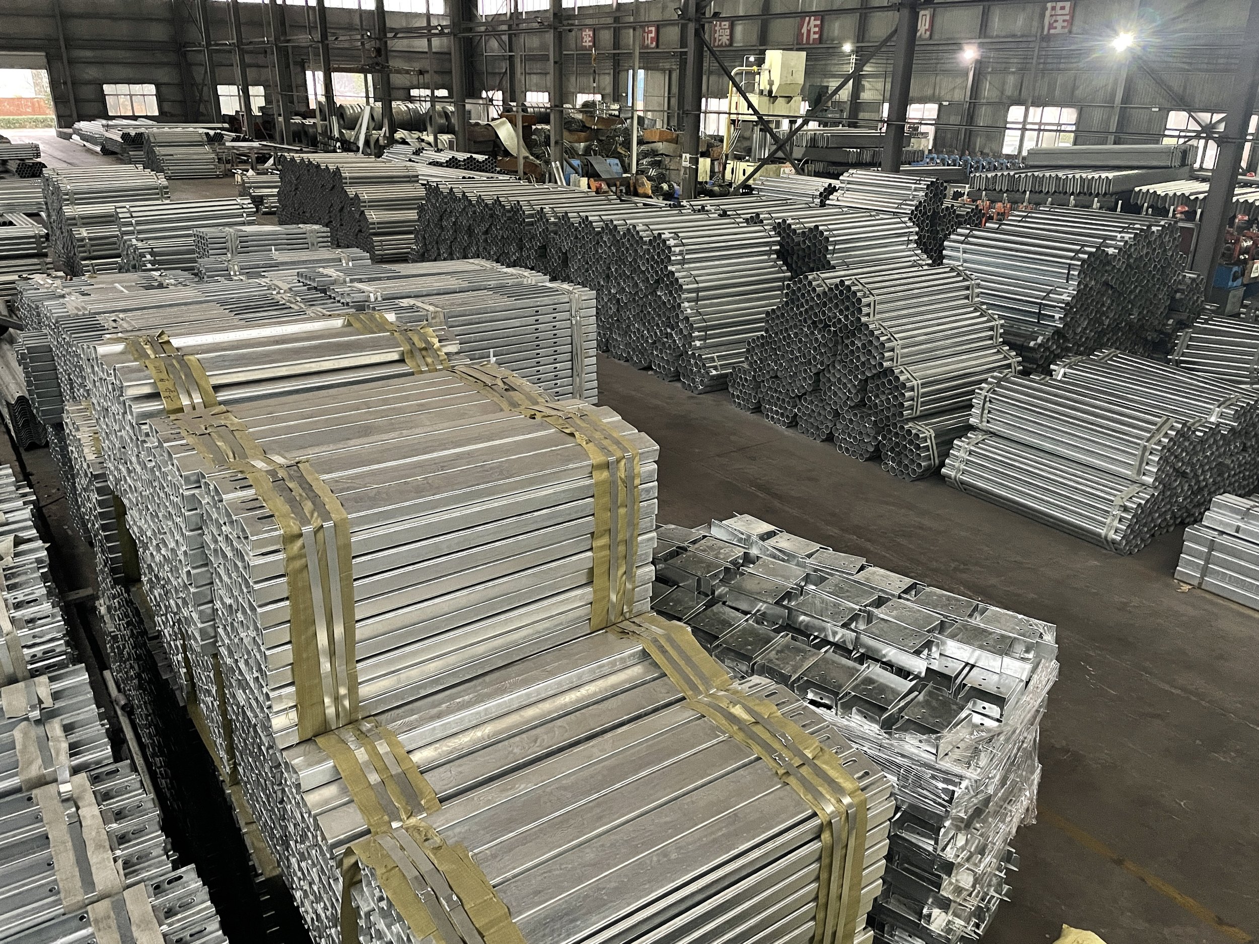 Stacks of metal pipes and fittings organized in a warehouse.