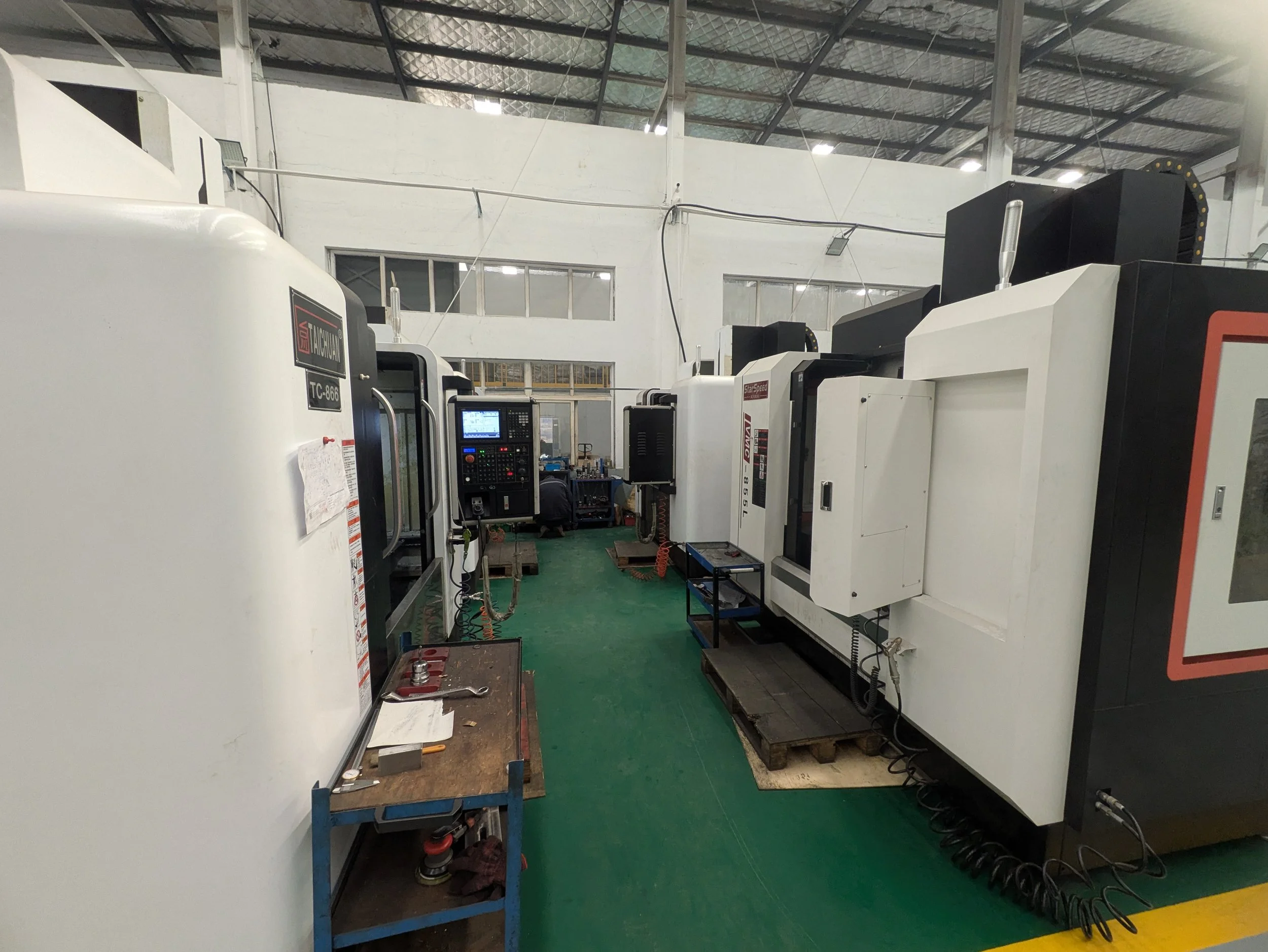 Industrial manufacturing facility with several CNC machines and a workbench in a spacious workshop