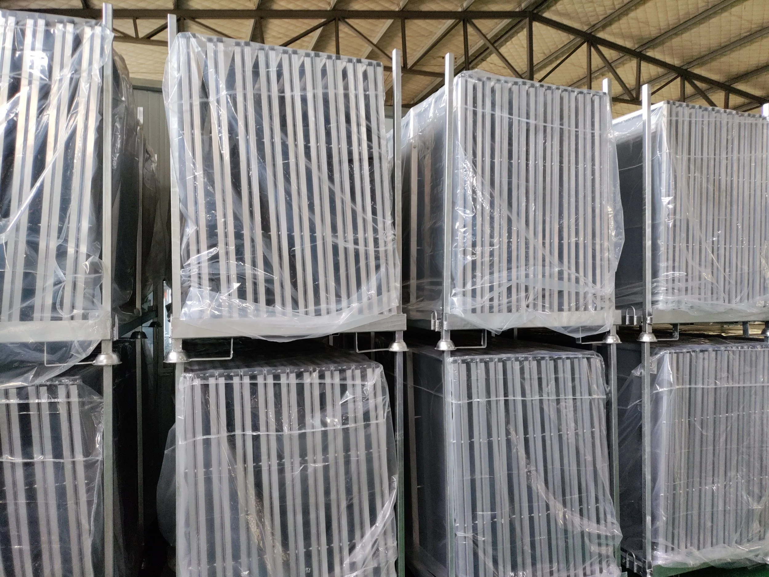 Stacked aluminum radiators wrapped in plastic in a warehouse.
