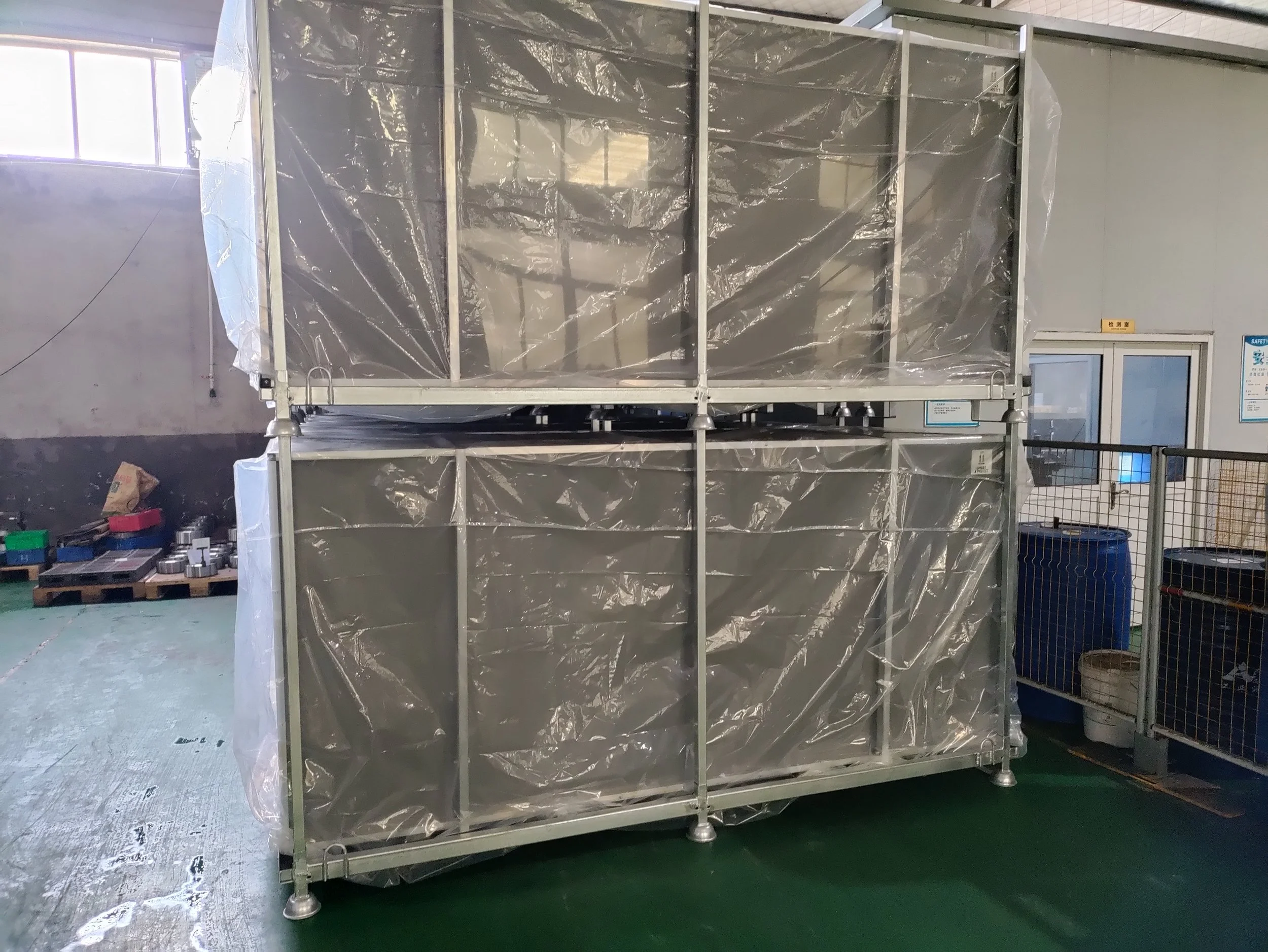 Large storage rack covered with clear plastic wrap in industrial setting.