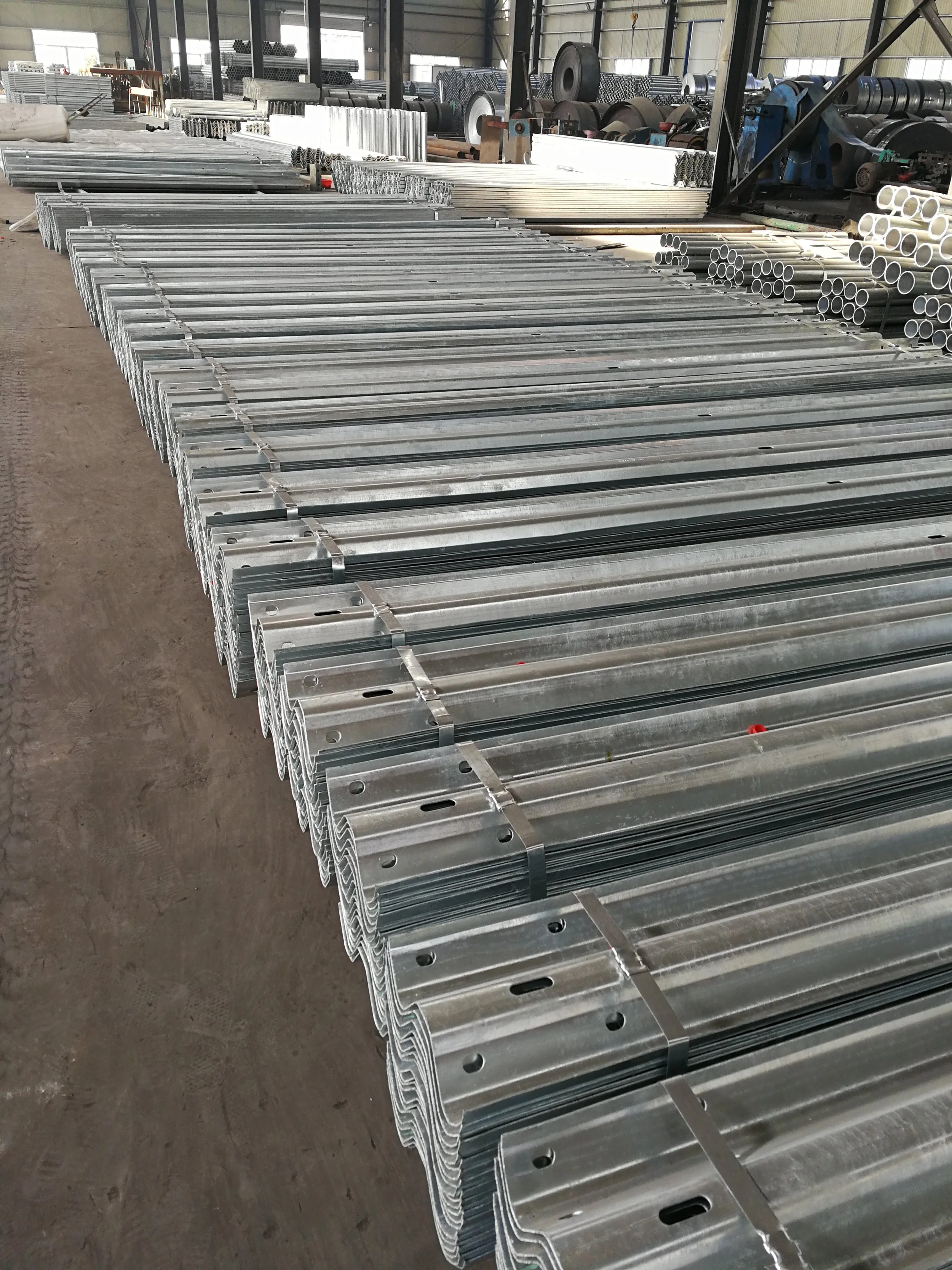 Metal pipes and brackets arranged in rows inside a warehouse or factory.