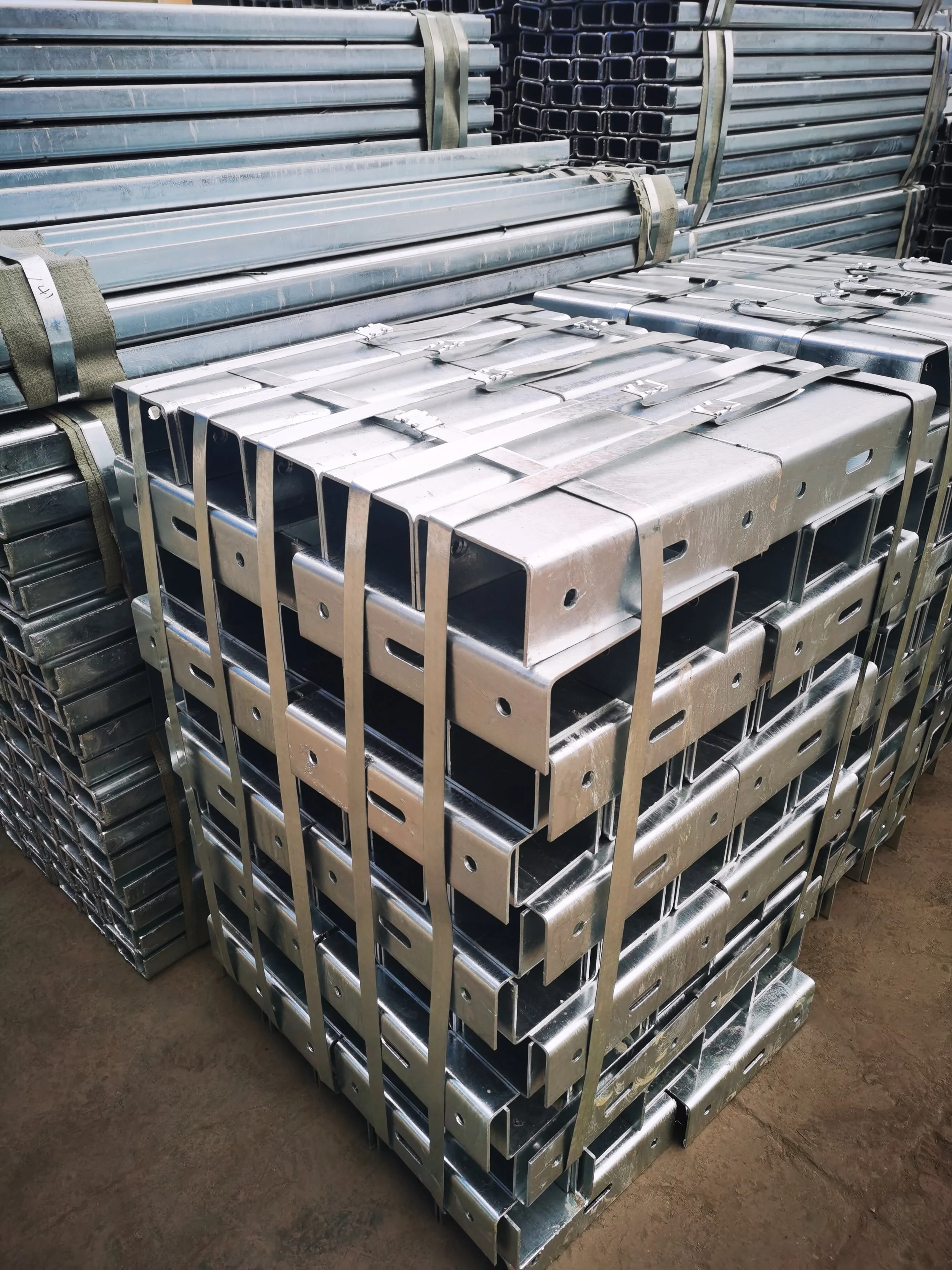 Stacks of metal scaffolding or construction beams bundled together in an industrial setting.