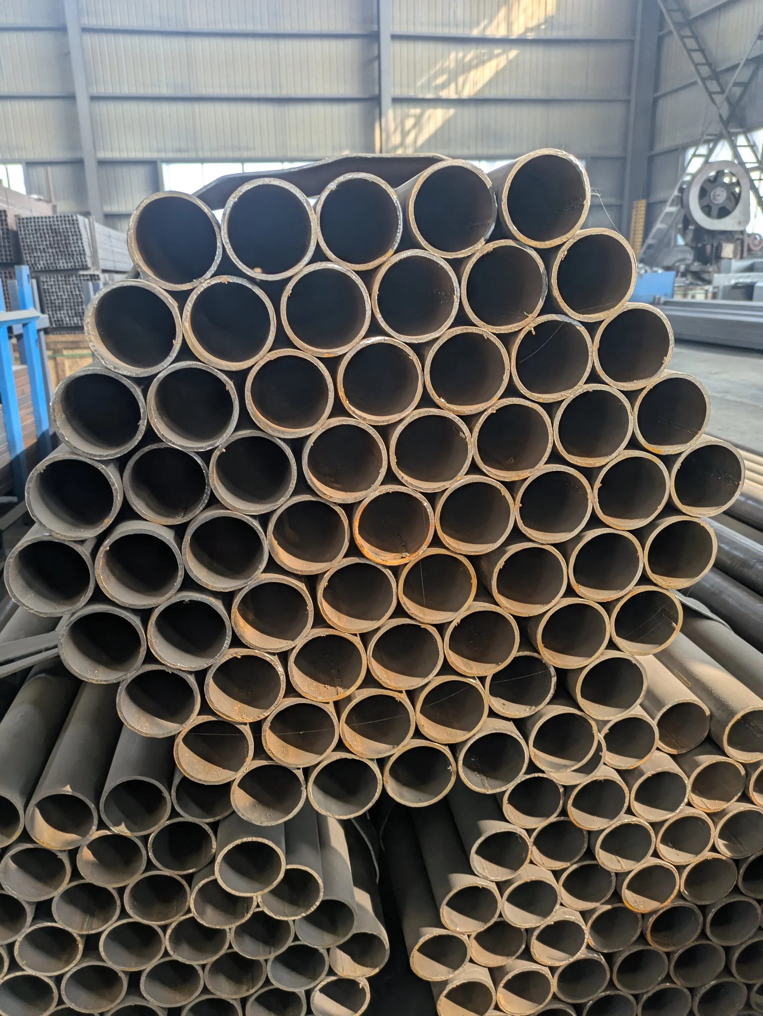 Stacked metal pipes inside a warehouse.