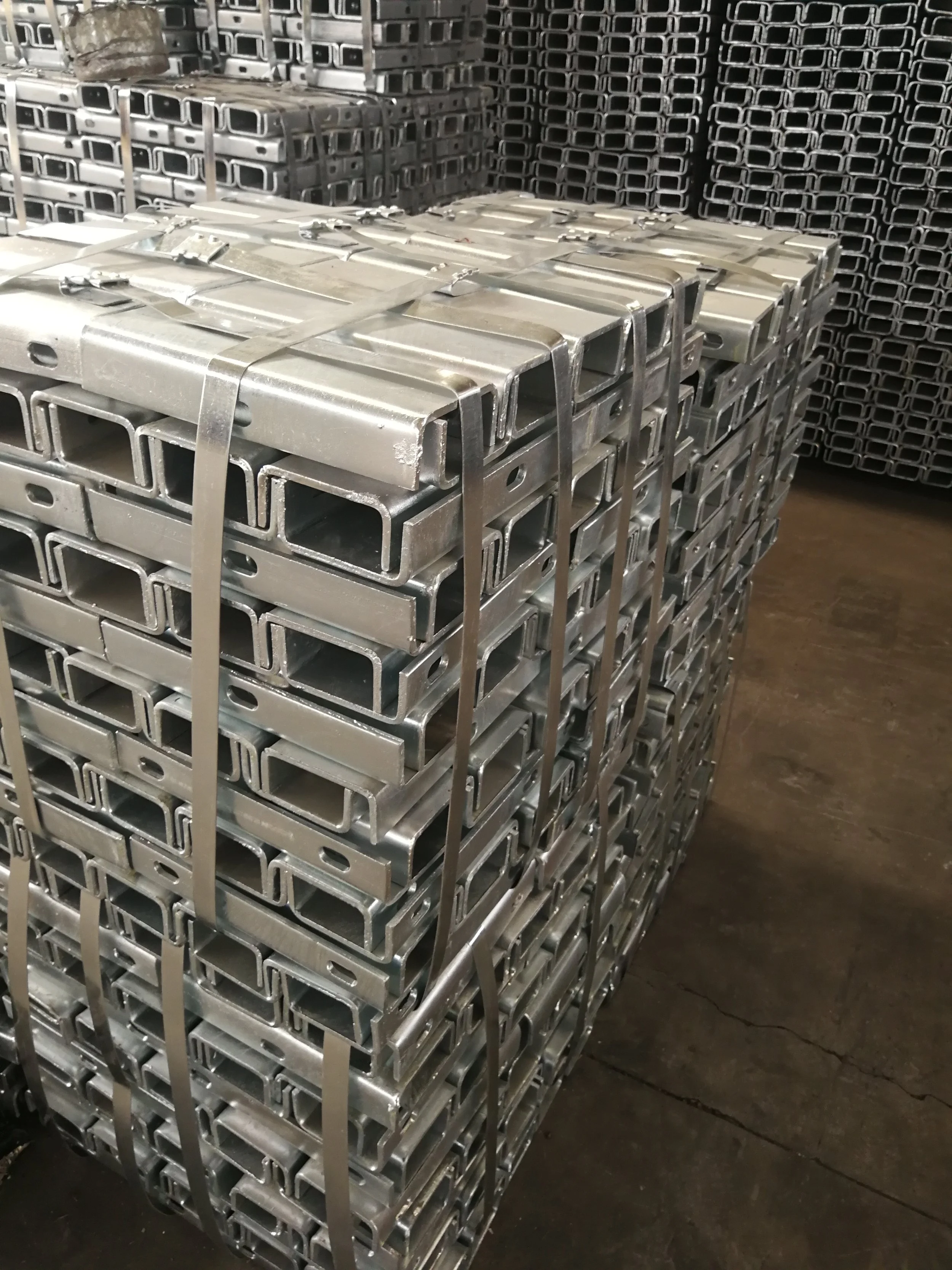 Stacked metal brackets or framing components on a pallet in an industrial warehouse.