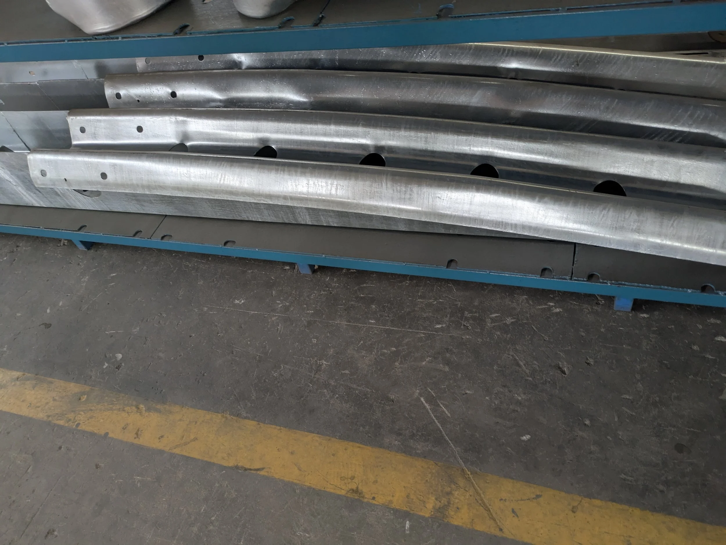 Metal structural beams stored on a blue rack in a warehouse or workshop.