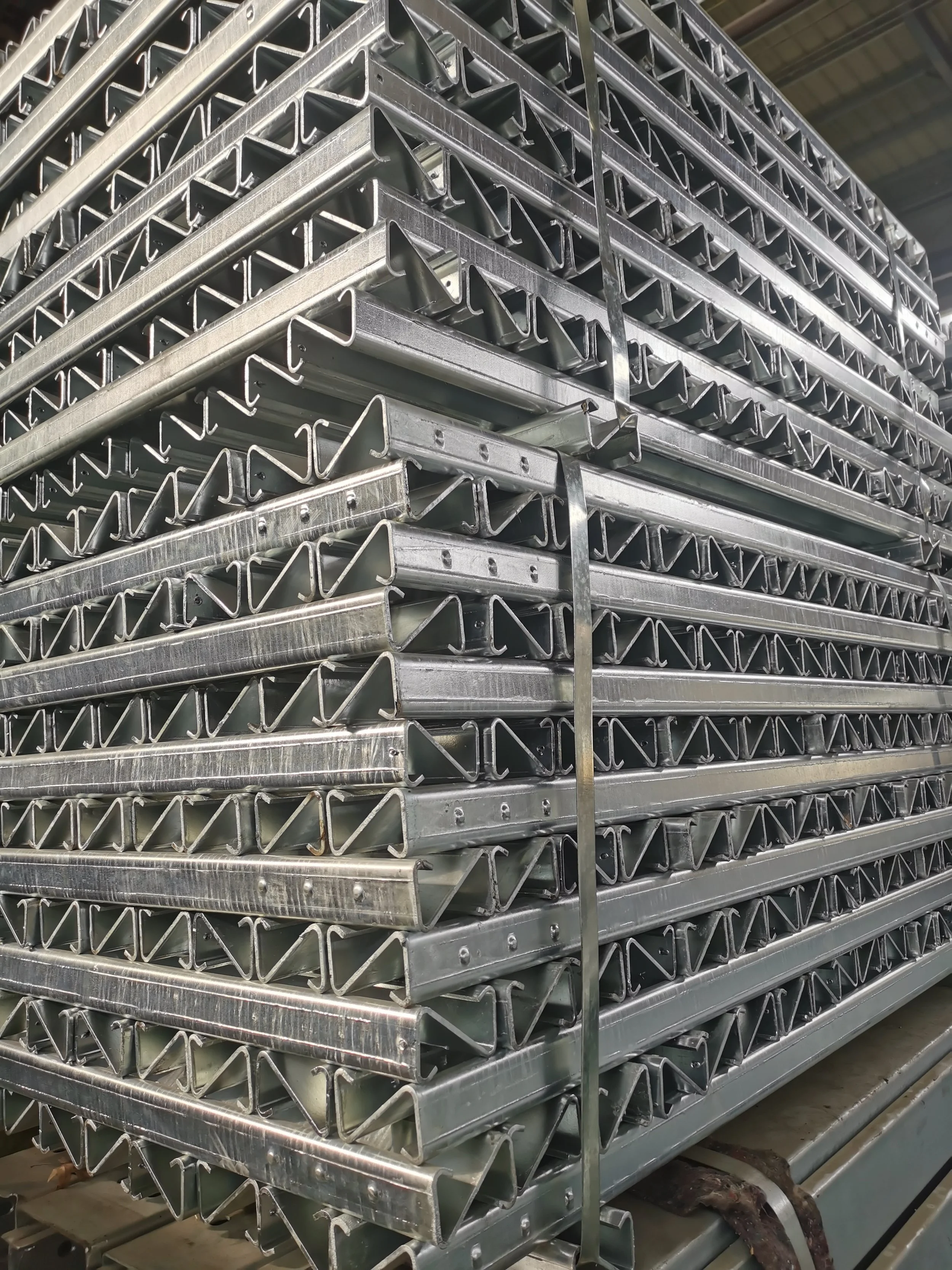 Stacked metal framing components likely used for construction or shelving, organized neatly in a warehouse setting.