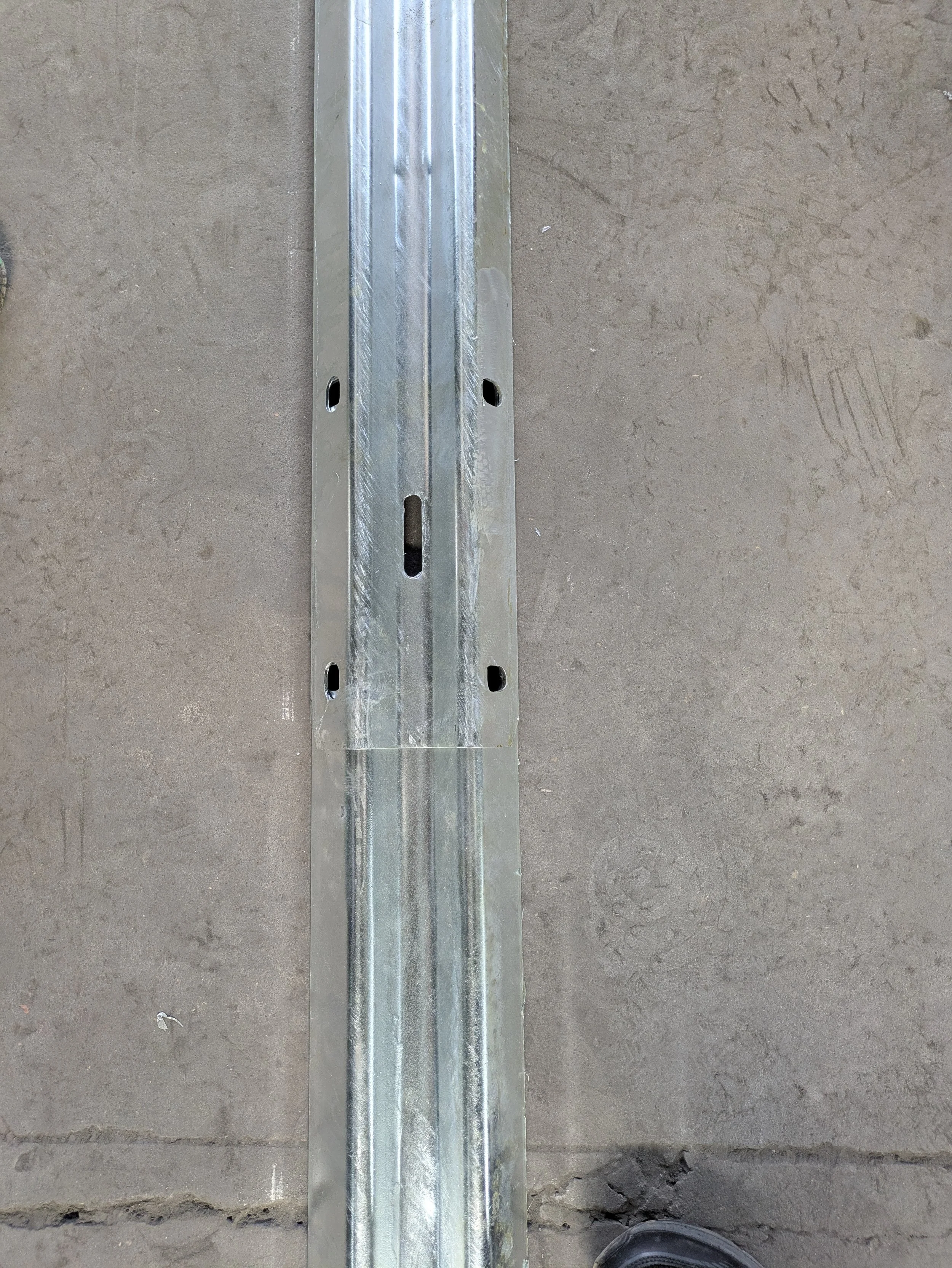 Steel framing rail on a concrete floor at a construction site.