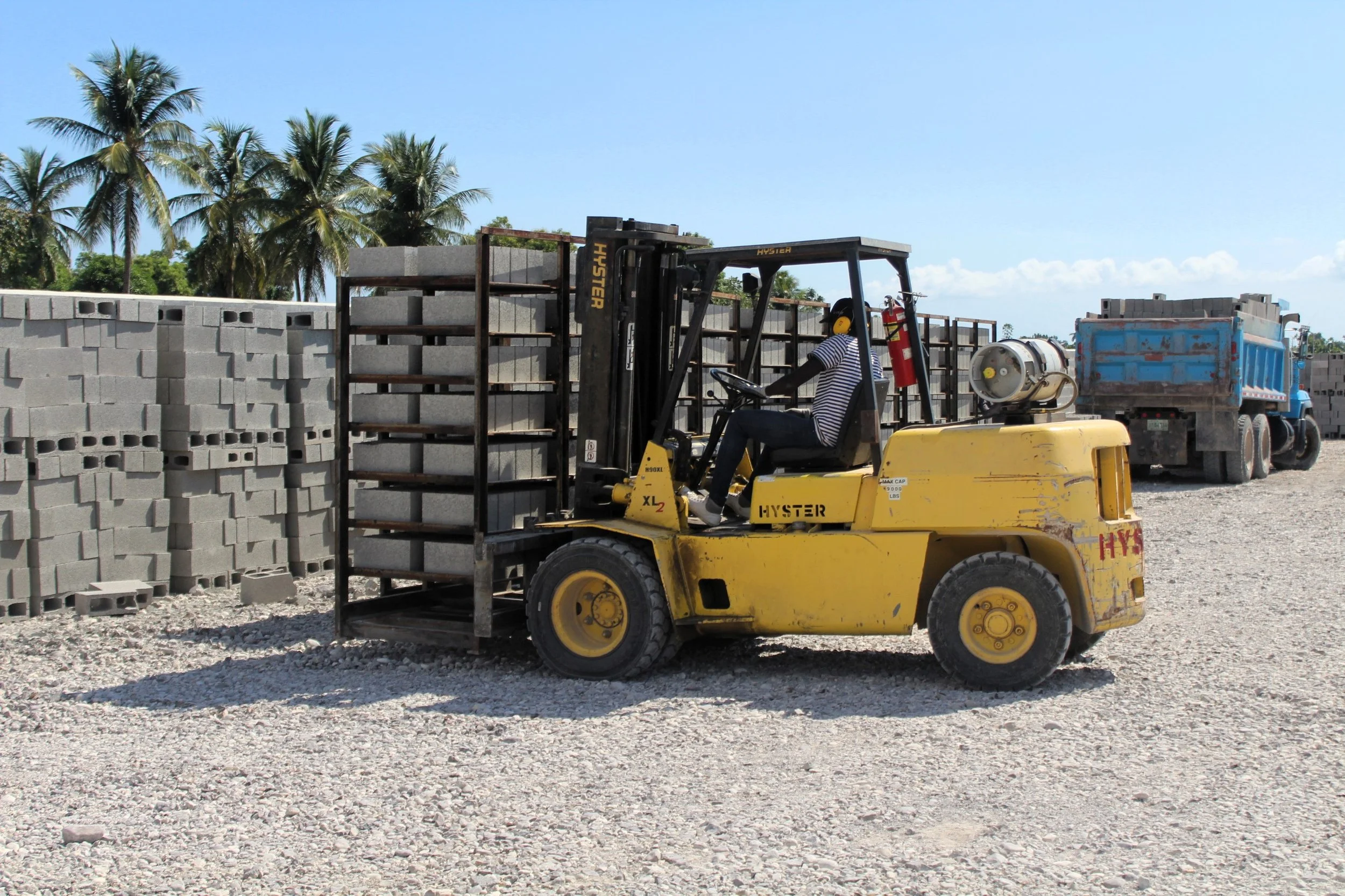 Haitian man operating a forklift, transporting cement blocks at the plant