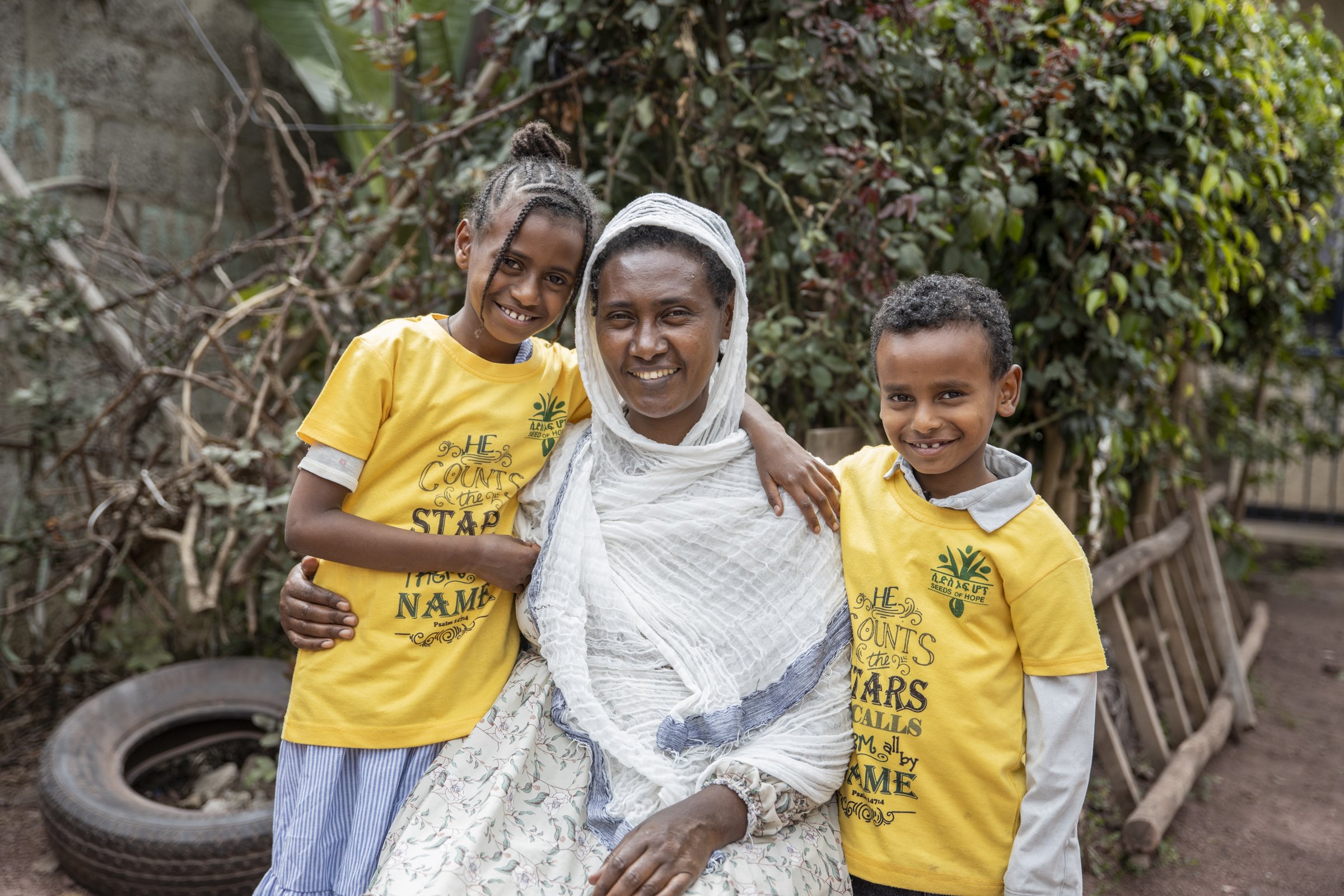 A mother smiling with her young daughter and son