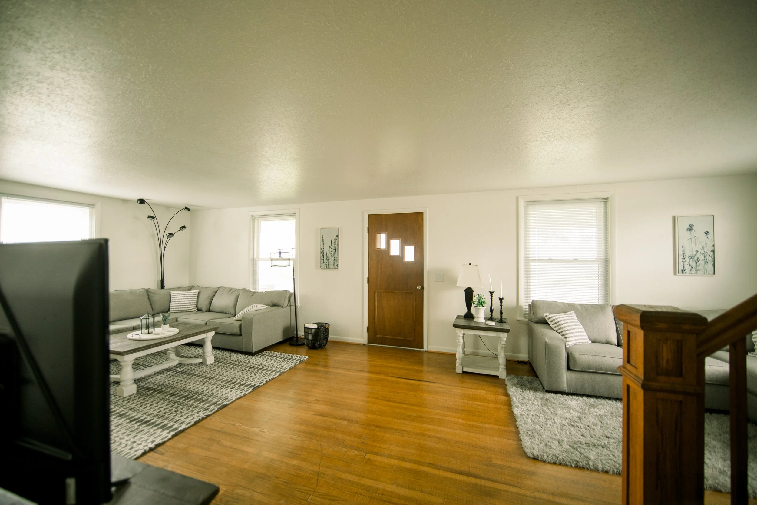 House entrance showing the TV, couches, coffee table, and front door. 