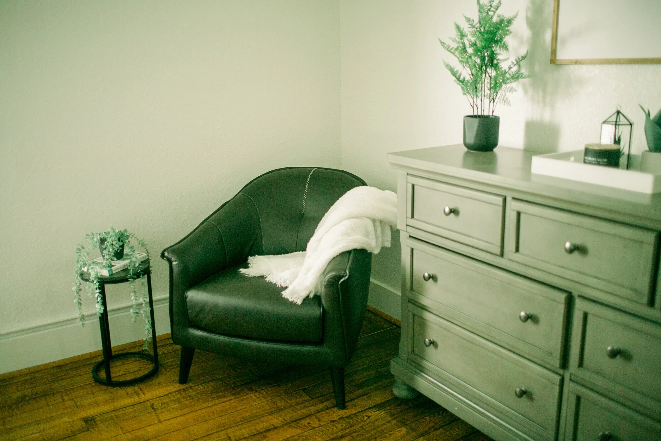 Leather chair with a blanket beside a dresser. 