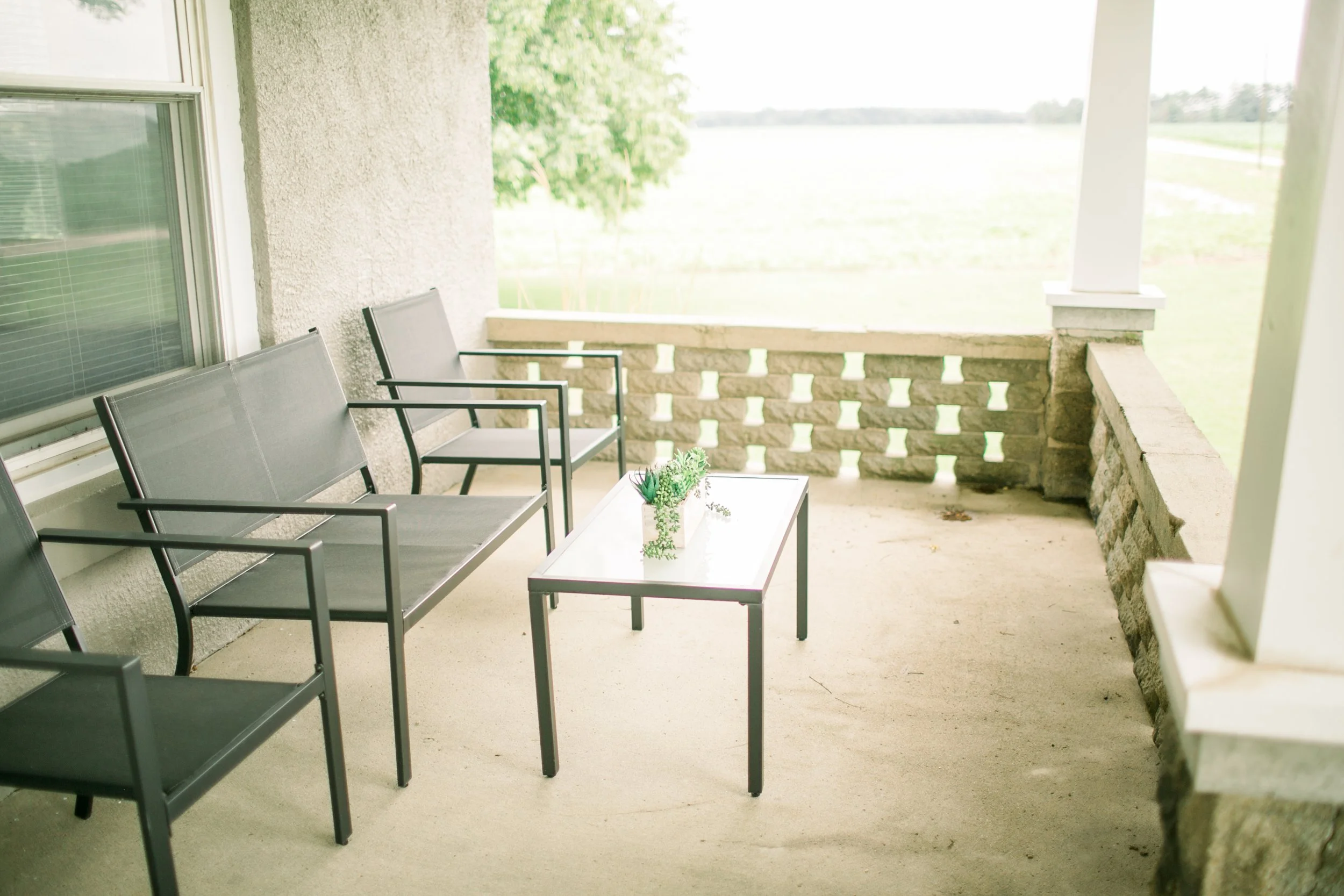 Outdoor patio with three chairs and a coffee table.