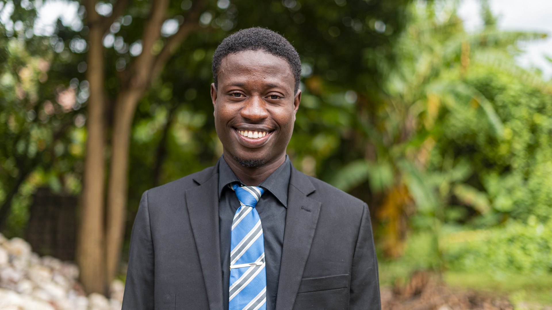 Young Haitian man smiling and wearing a suit.