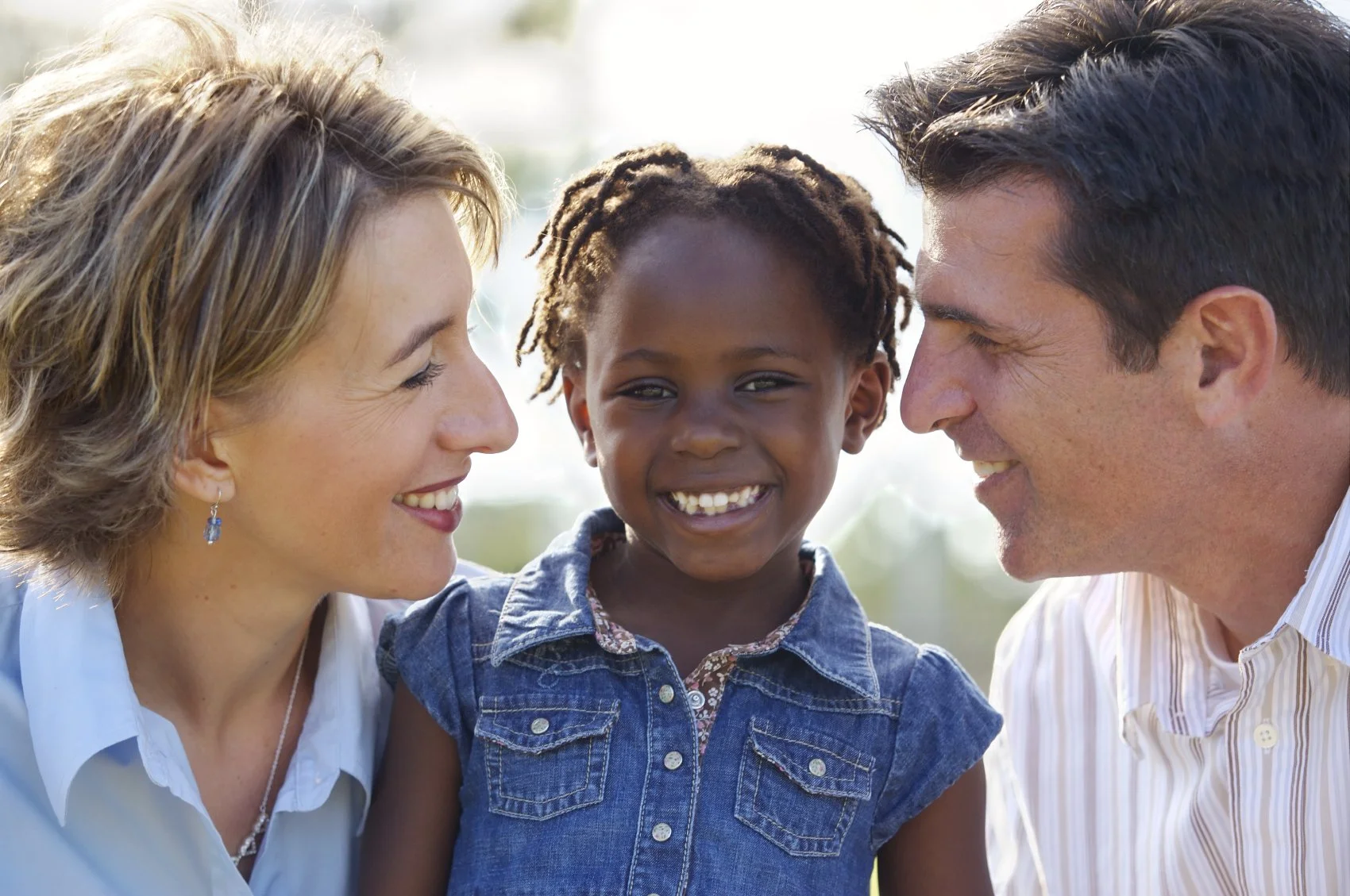 American mother and father smile at their adopted little girl