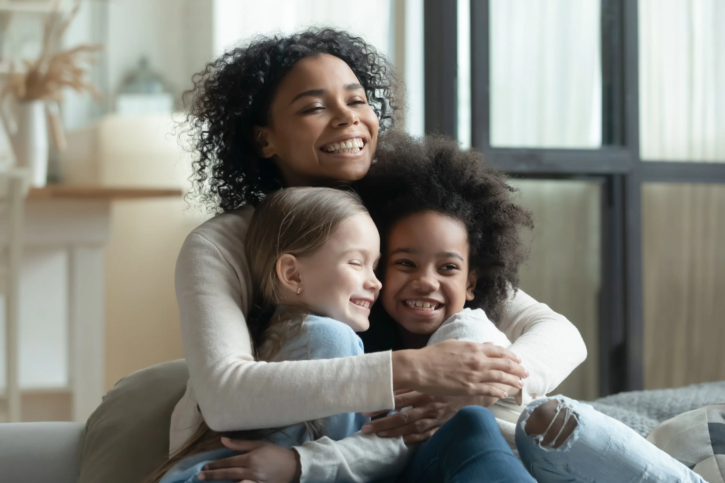 Mother smiling and hugging her two young daughters
