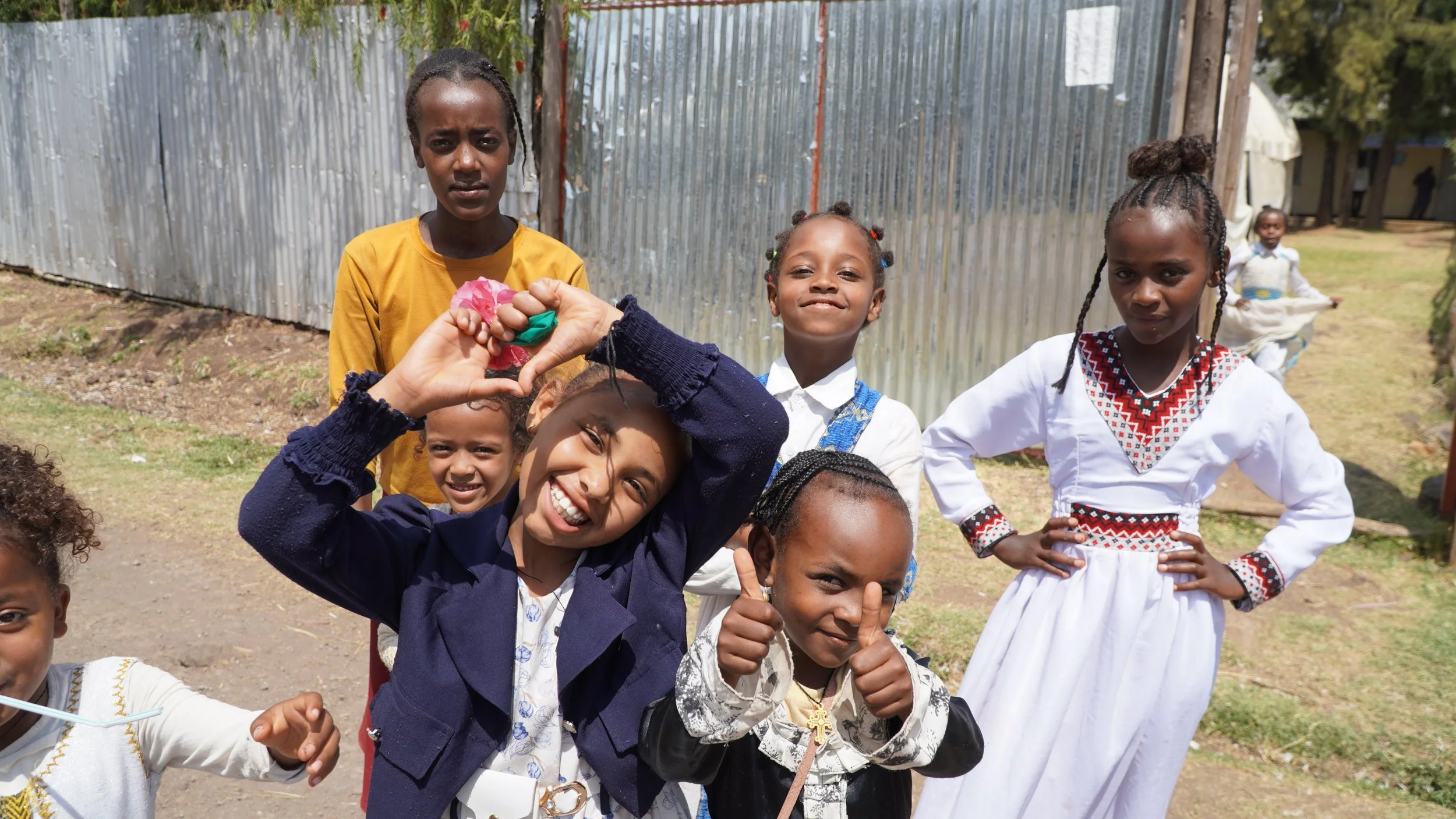 Little girls laughing and posing with thumbs-ups and hands forming hearts