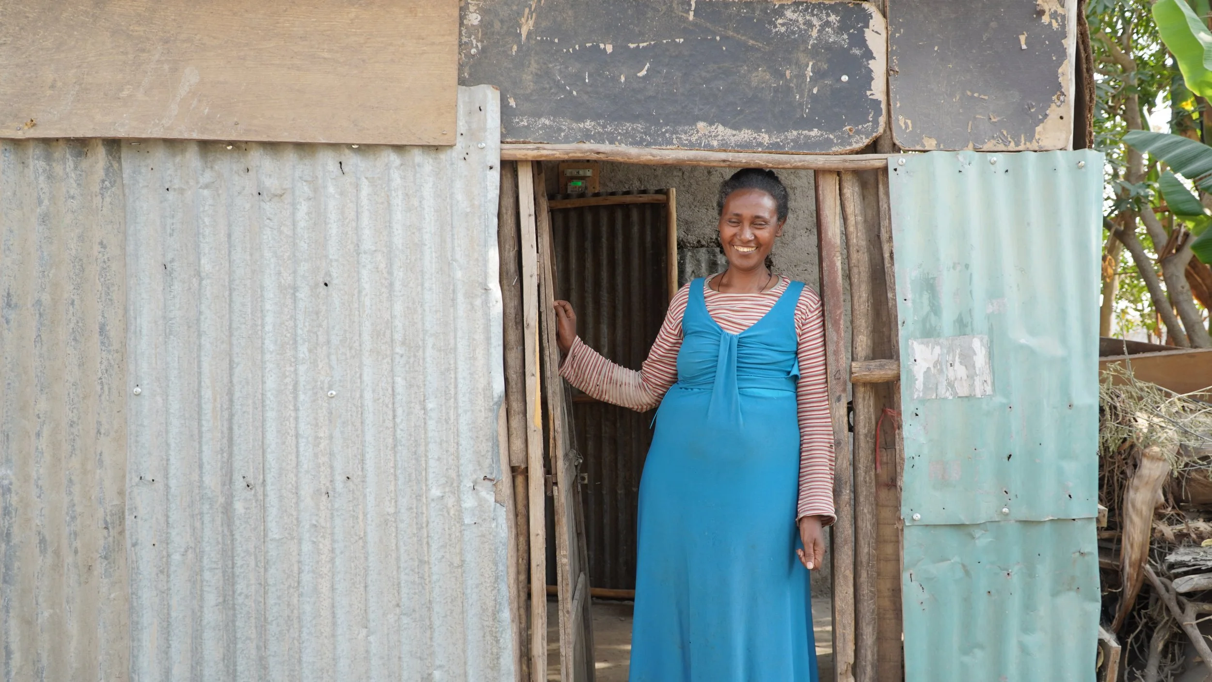 A mother smiling as she stands in the doorway of her home