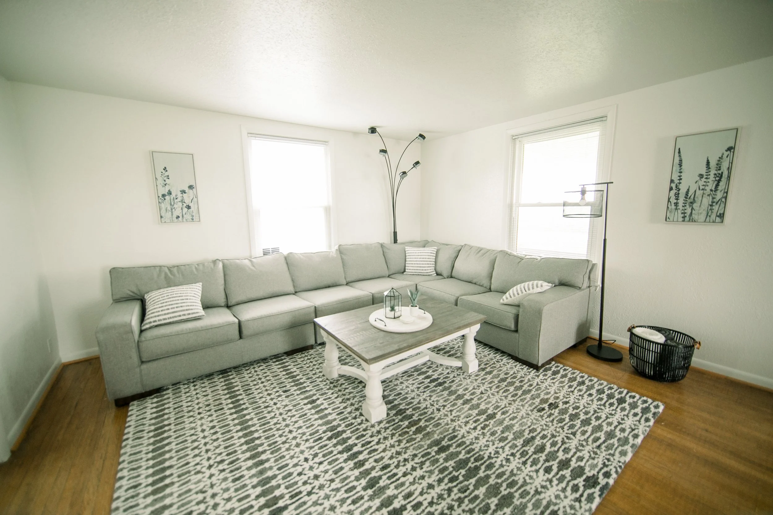 Living room with large couch, windows, and a coffee table