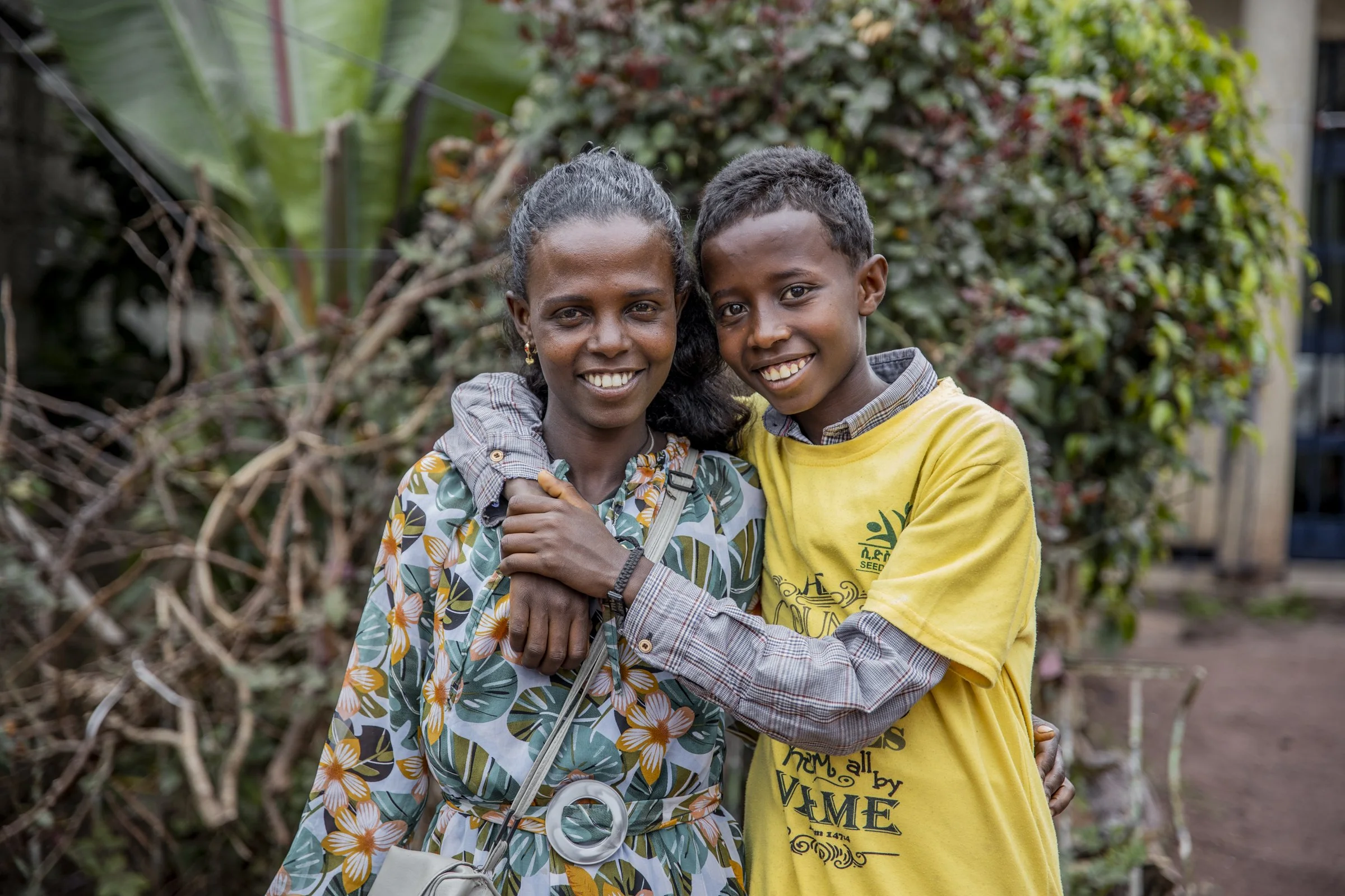 A young mother smiling as her son hugs her