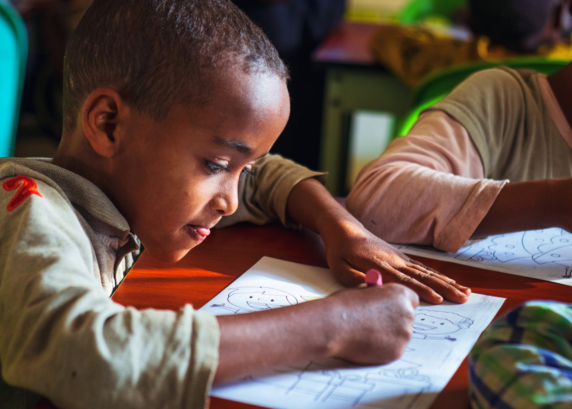 A little boy concentrating on coloring a picture in a classroom