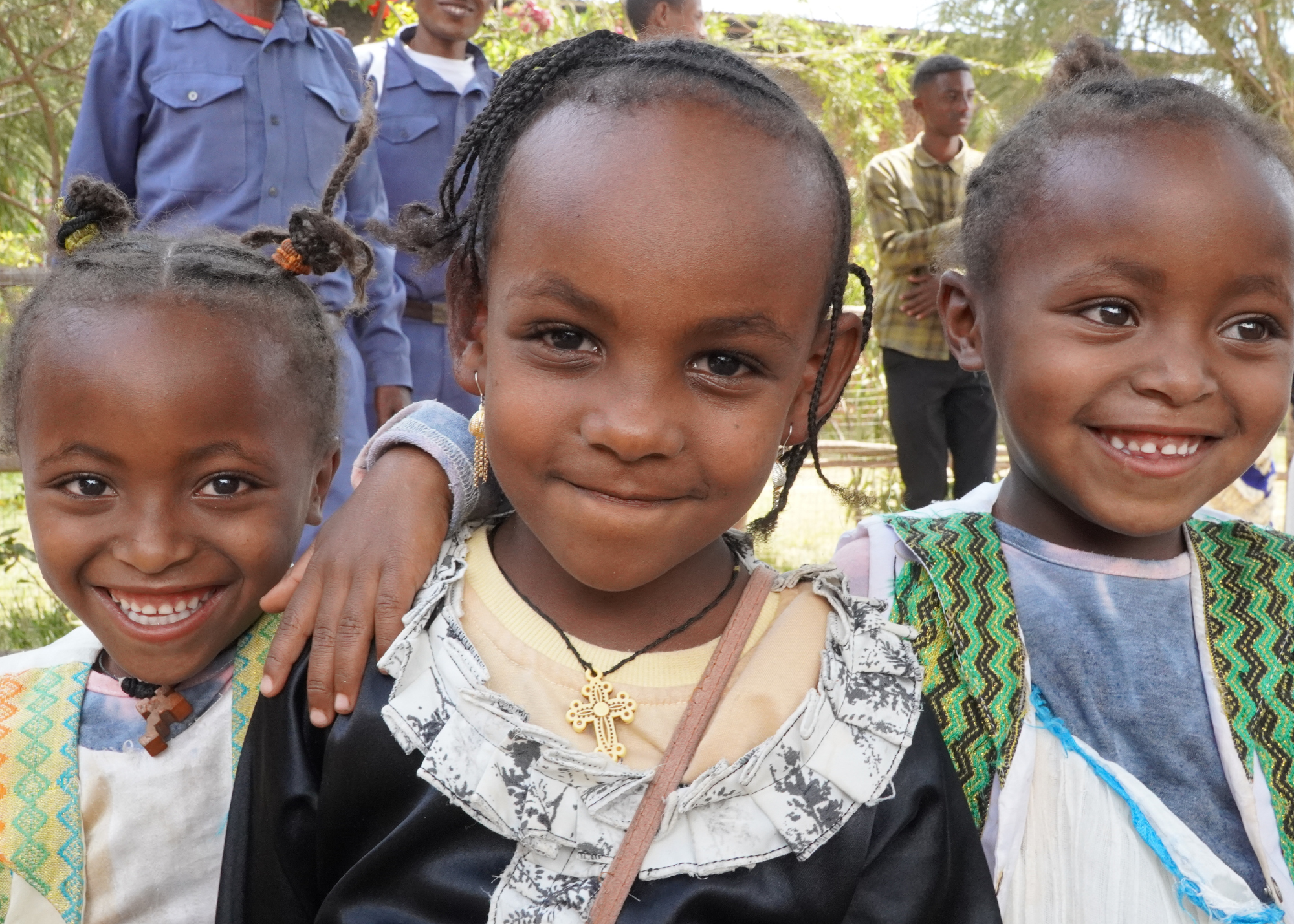 Three little girls smile and have their arms around each other