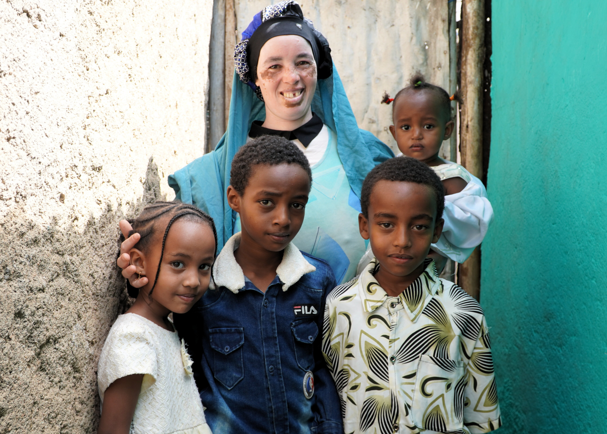 Young mother holding her baby girl and standing with her other daughter and two sons